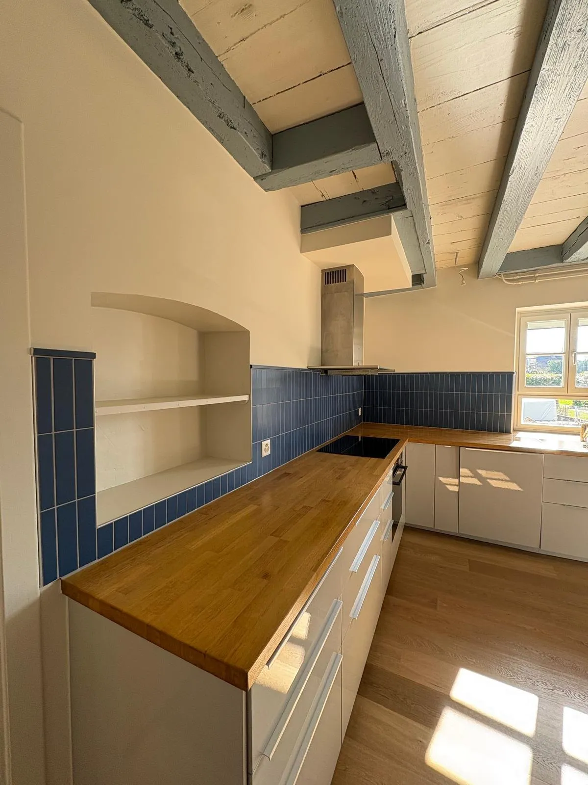 Crédence de cuisine carrelée le long d’un plan de travail, avec niche murale et plaque de cuisson
