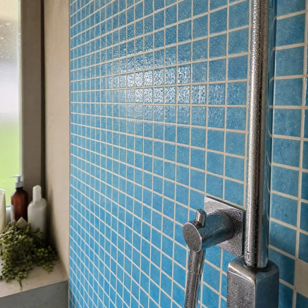 Paroi de douche carrelée en mosaïque bleue avec colonne de douche chromée