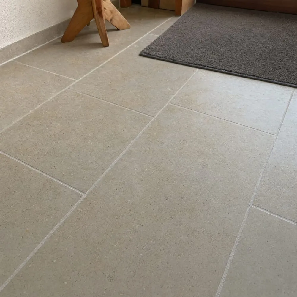 Sol en grands carreaux beige clair effet pierre avec tabouret en bois