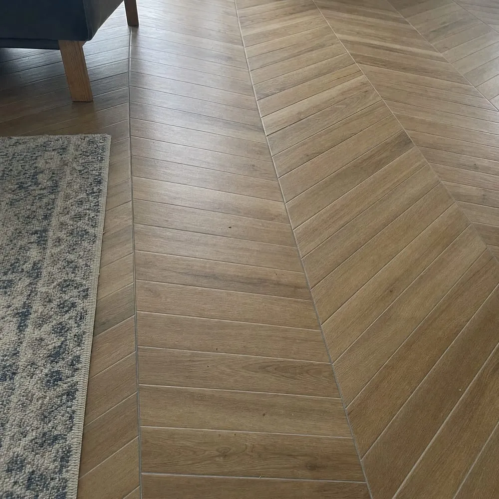 Sol en carrelage imitation bois posé en chevron dans une pièce à vivre