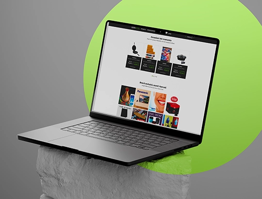 Computer portatile aperto appoggiato su base bianca con cerchio verde sullo sfondo, mostra un sito web.