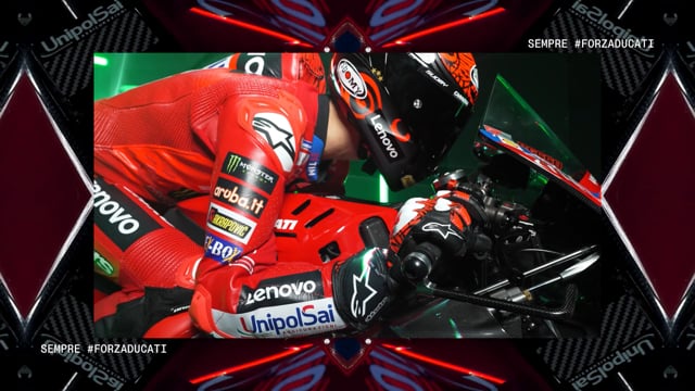 Pilota MotoGP con tuta rossa e casco nero su moto da corsa rossa Lenovo e UnipolSai.