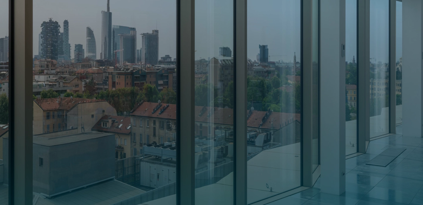 Vista della skyline di Milano con grattacieli vista da ampie finestre di un edificio moderno.