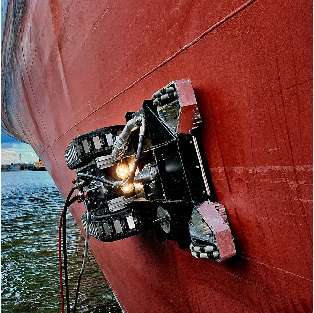 Close-up of the magnetic-adhesion cleaning robot attached to a red ship hull