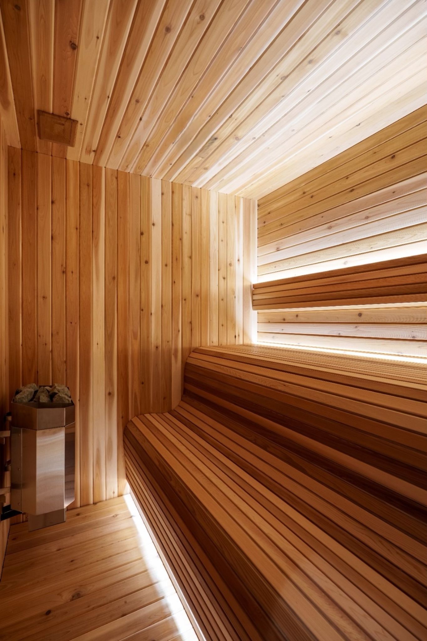 Wood-lined home sauna with tiered benches and integrated lighting