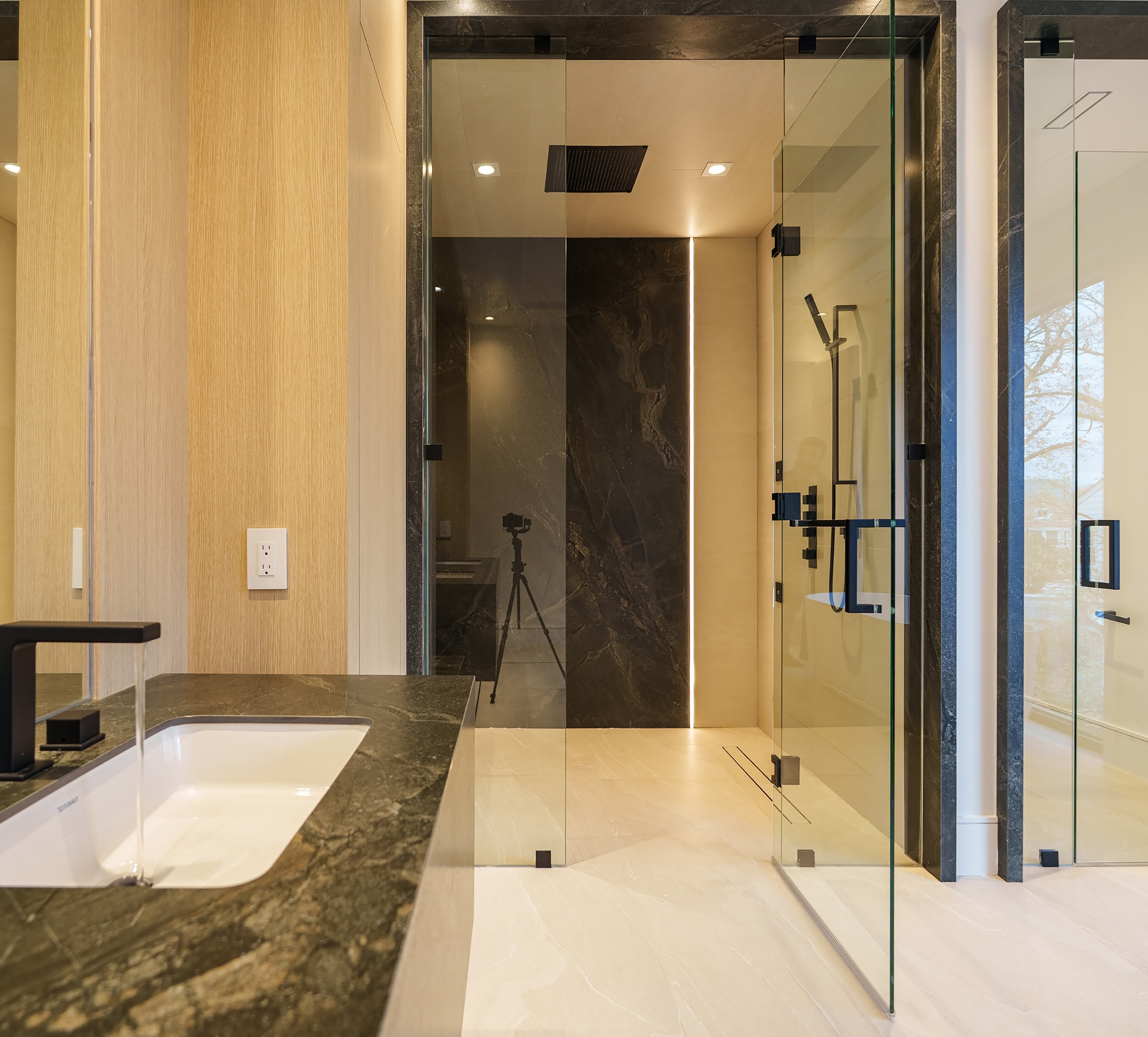Modern bathroom with stone vanity, glass shower, and warm wood finishes