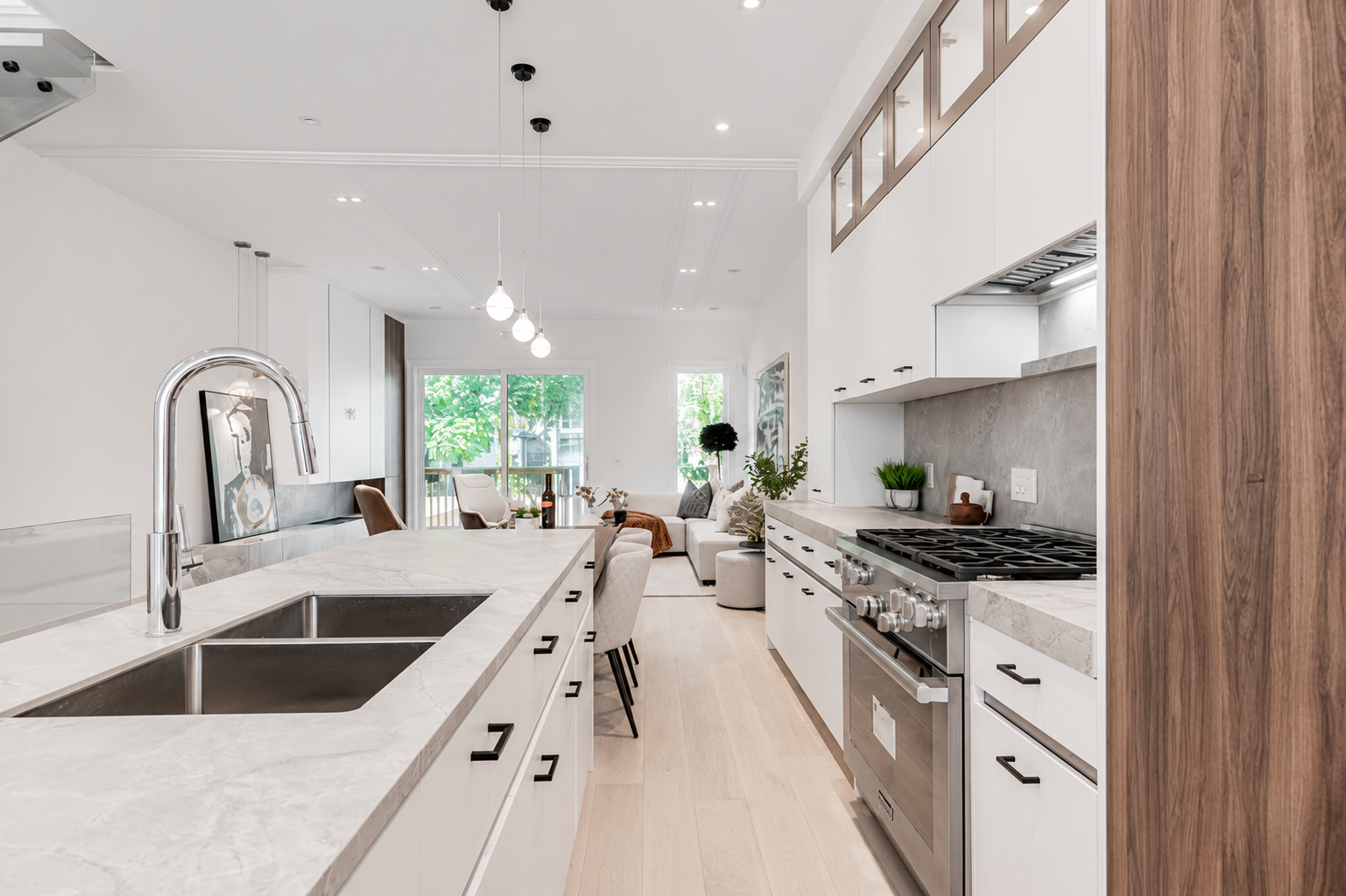 Galley kitchen with marble countertops opening into a bright living area