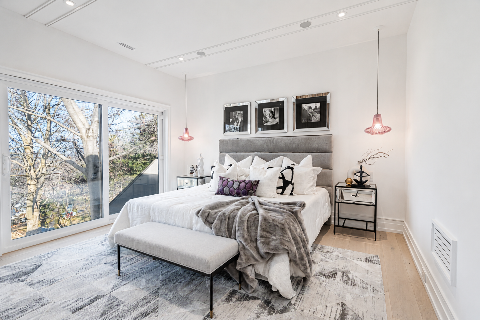 Bright bedroom with upholstered bed, pendant lights, and large window