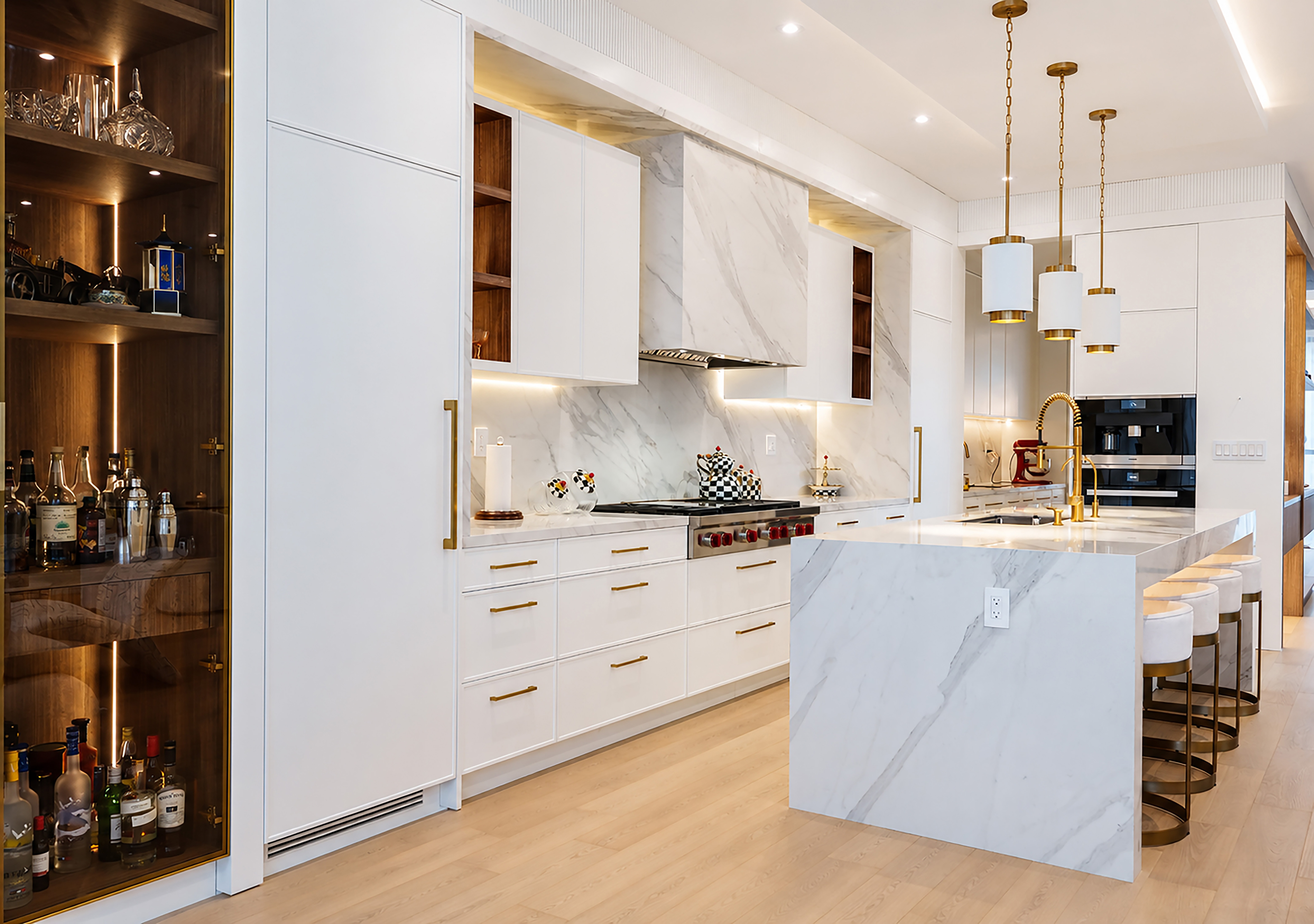 Bright white kitchen with marble island, gold accents, and concealed bar cabinetry