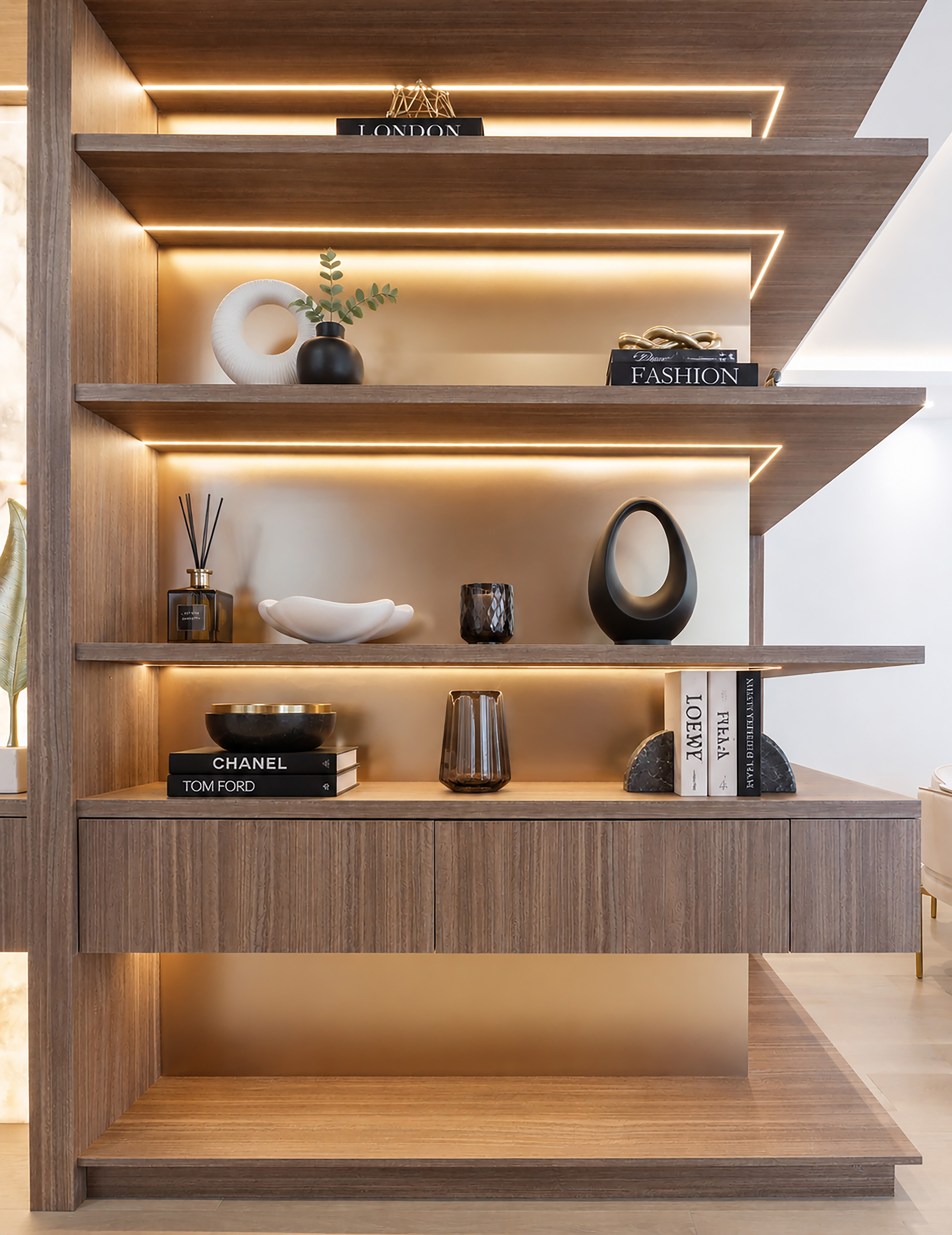 Close-up of illuminated wood shelving styled with books and decorative objects
