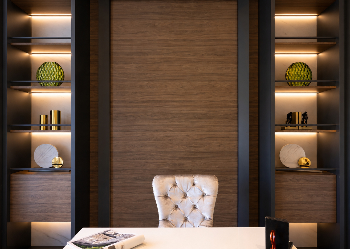 Home office with dark wood wall panels, integrated shelving, and warm lighting