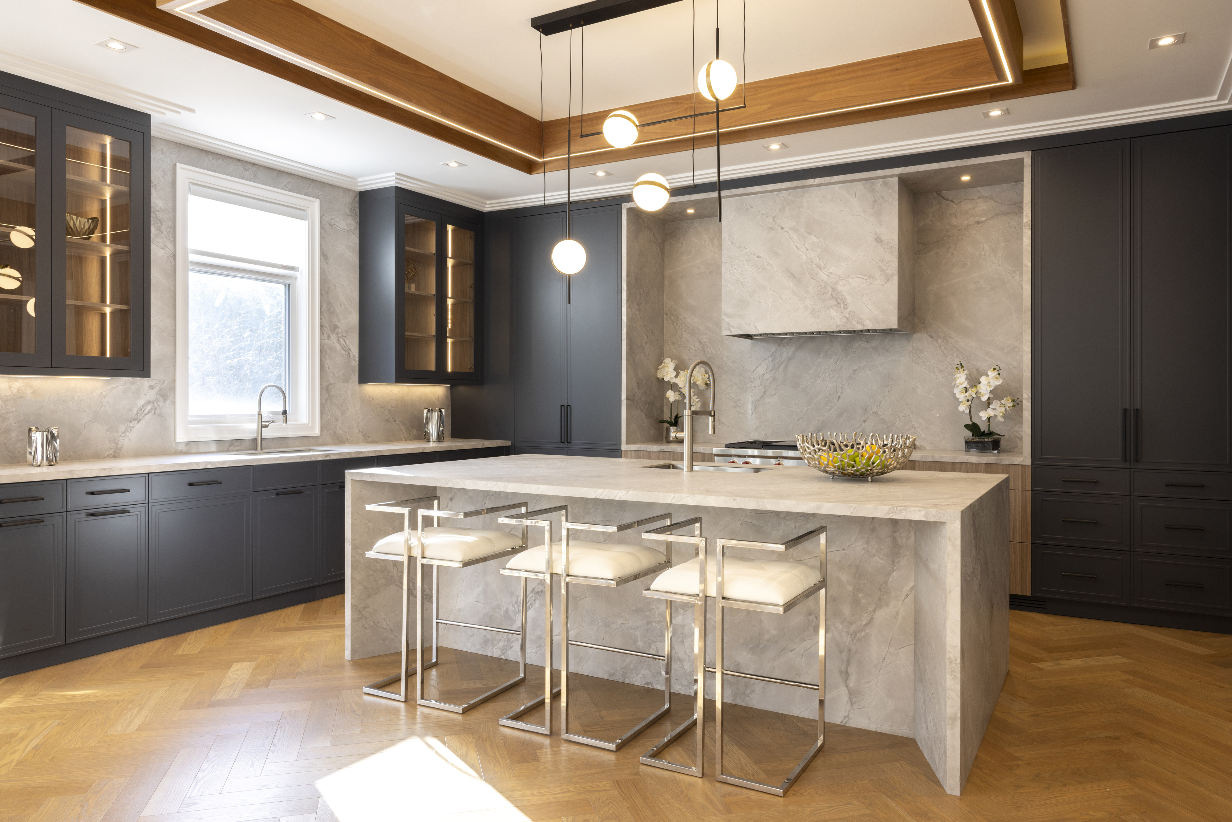 Modern kitchen with dark cabinetry, stone island, and warm wood ceiling accents