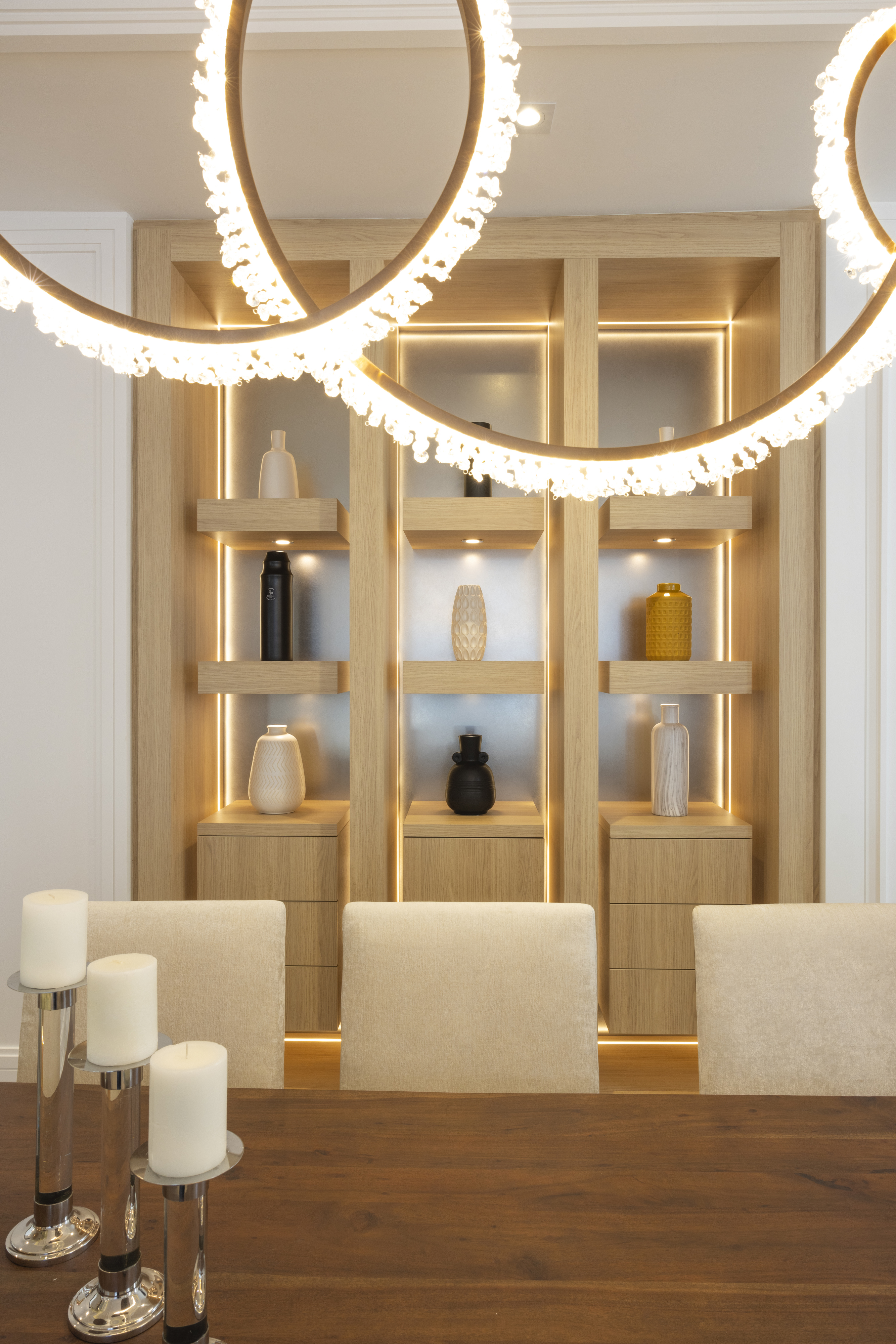 Illuminated light wood display shelving with decorative objects behind a dining area