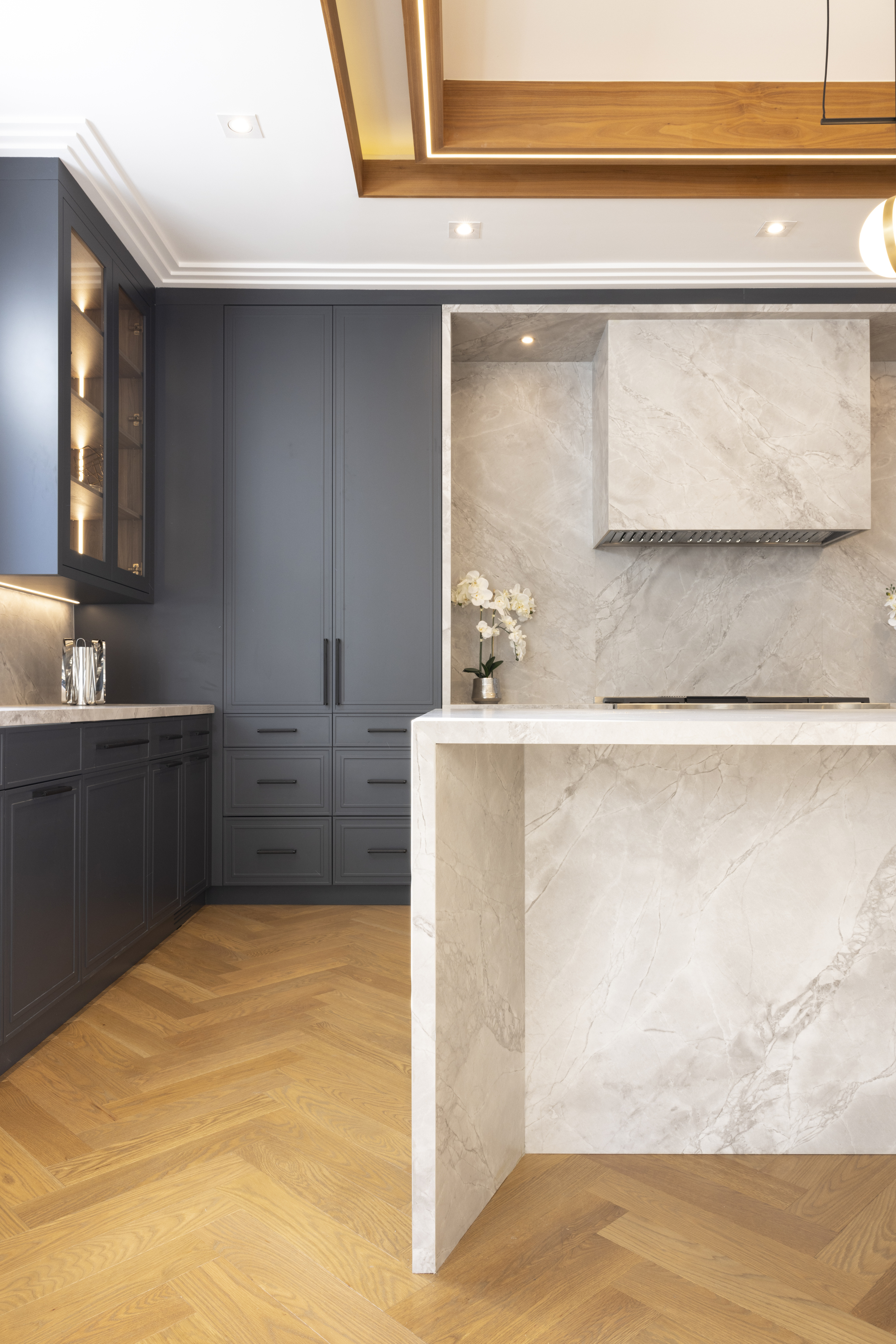 Close-up of dark kitchen cabinetry, stone backsplash, and waterfall island