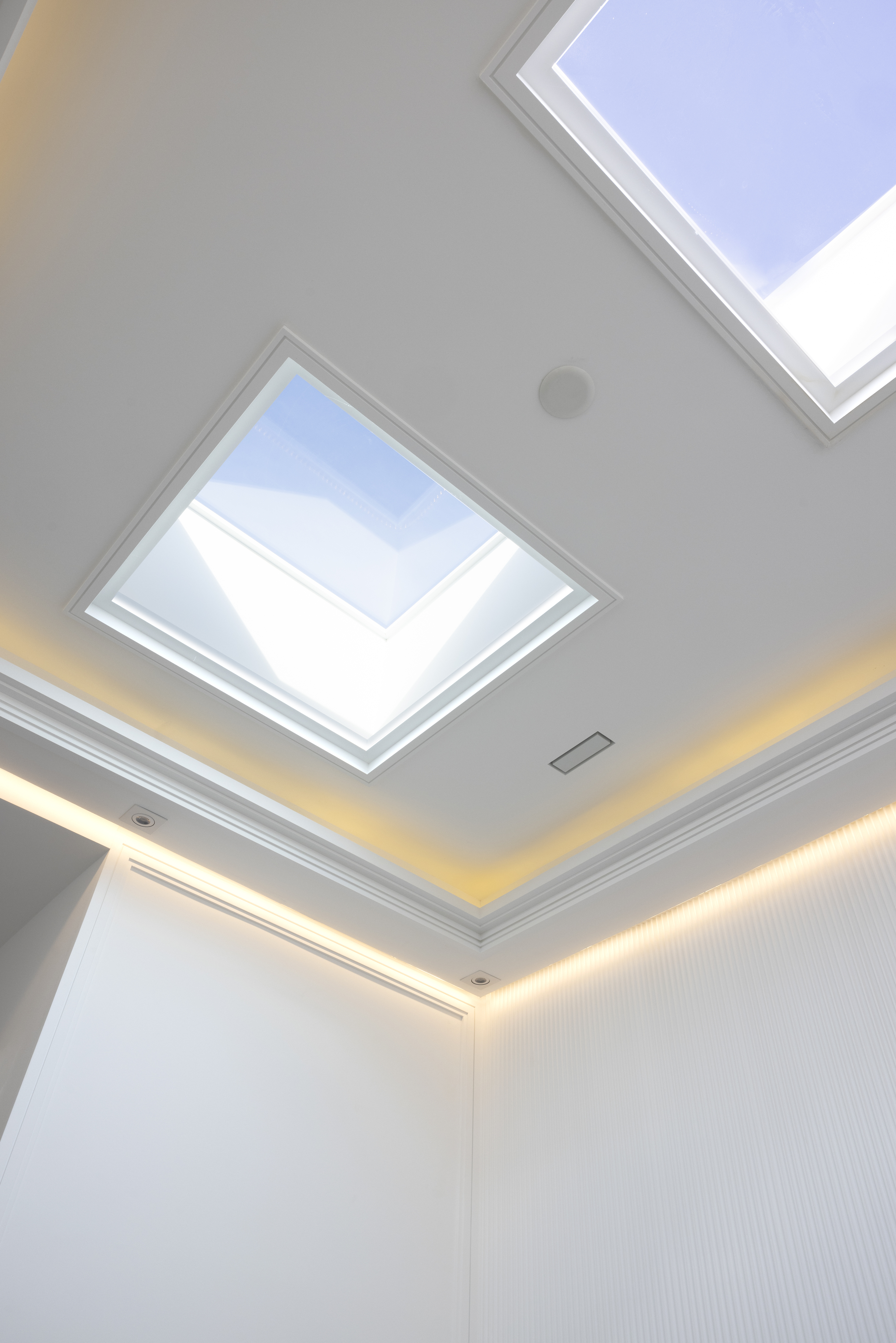 Recessed ceiling skylight surrounded by warm cove lighting