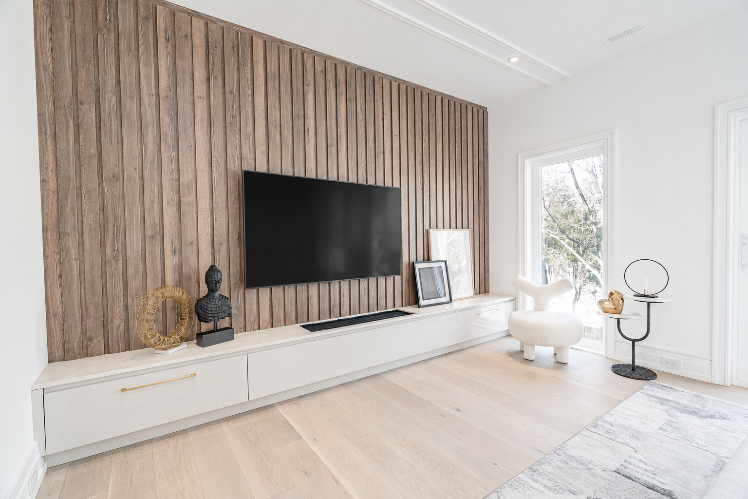 Bedroom with wood slat television wall, low white cabinetry, and pale wood flooring