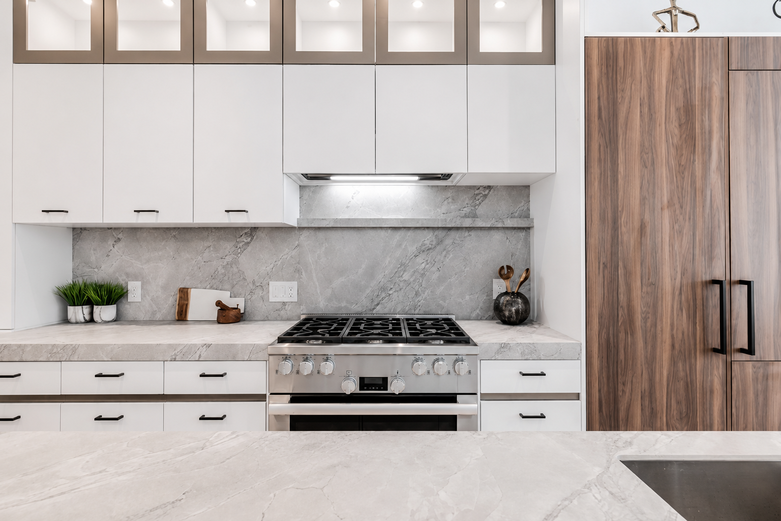 White kitchen with marble backsplash, stainless steel range, and tall wood cabinetry