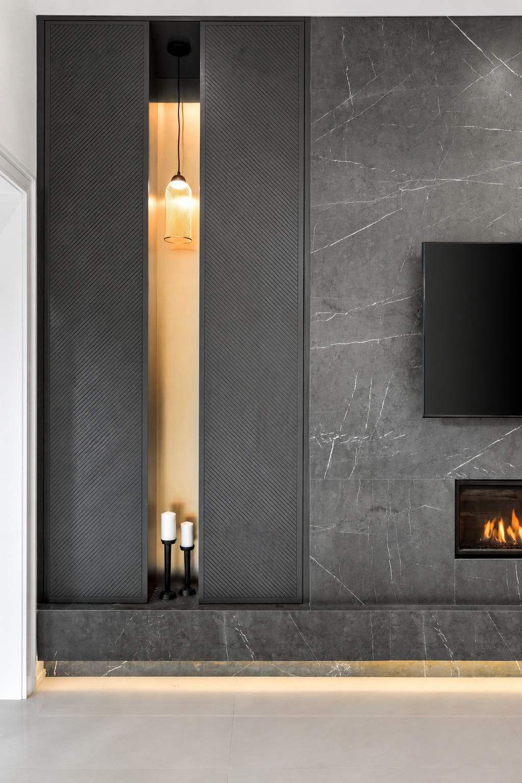 Dark fluted cabinetry beside a grey stone television wall, fireplace, and warm illuminated niche