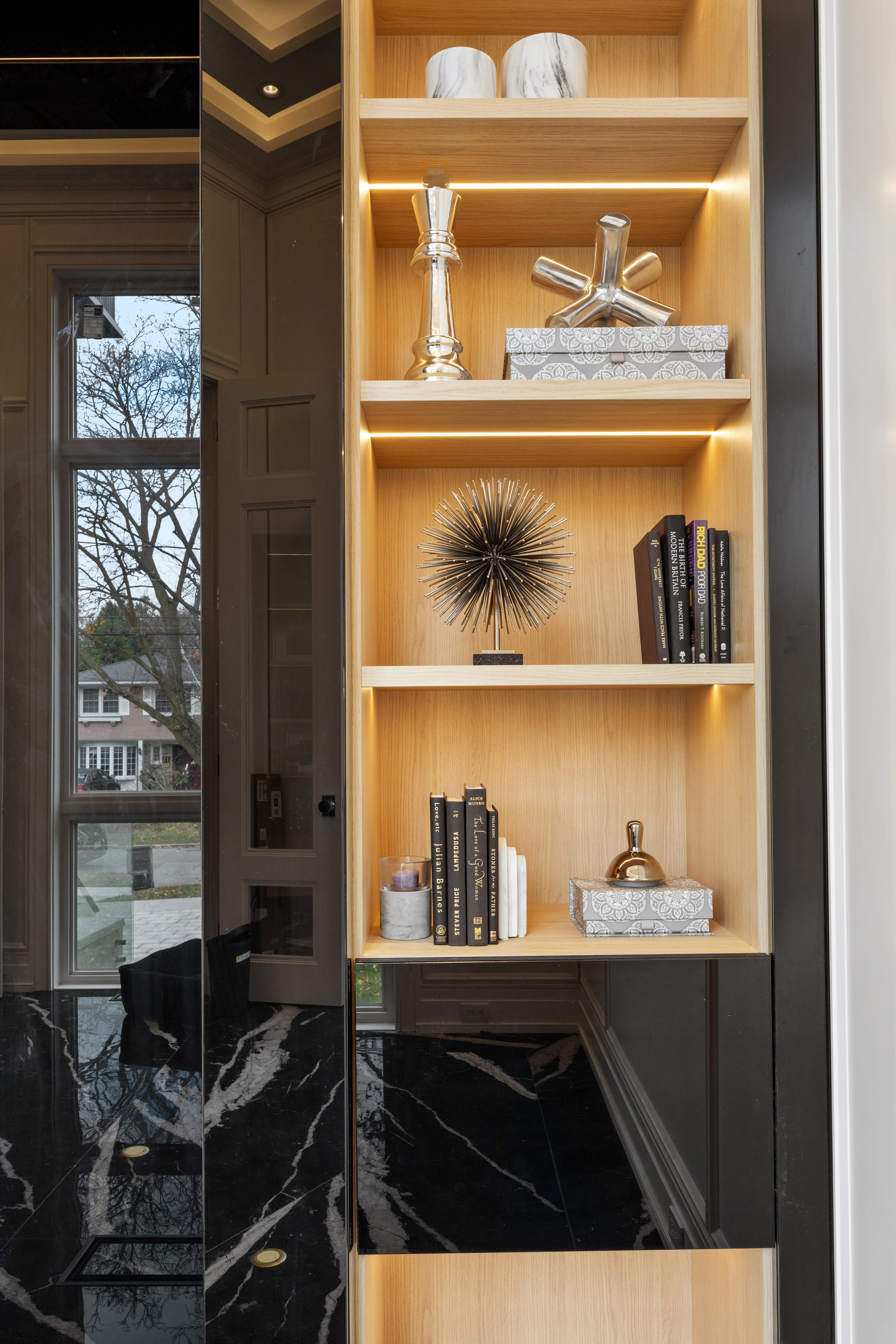 Illuminated wood display shelving beside a dark-framed window and door
