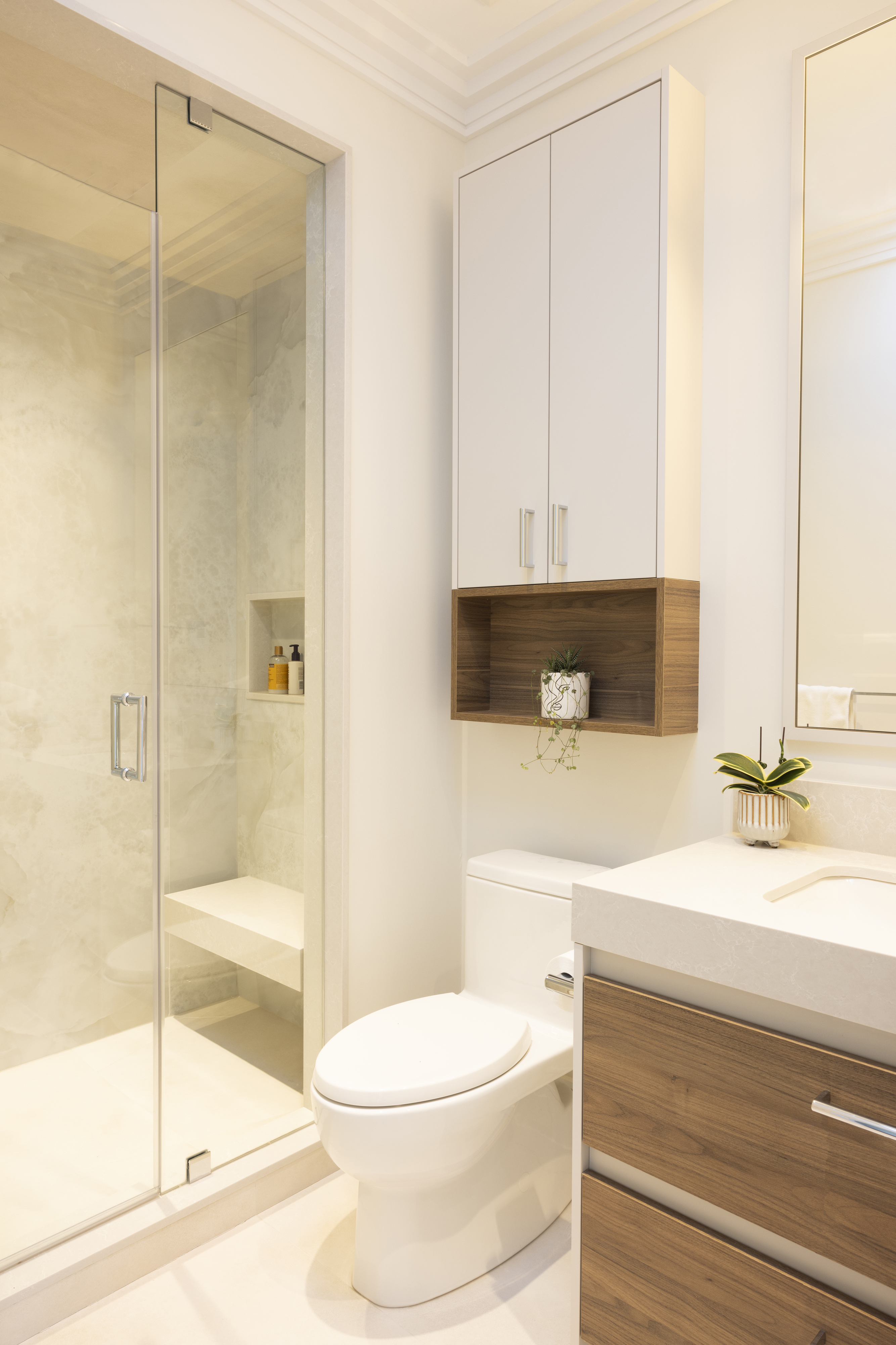Modern bathroom with glass shower, white vanity, and wall-mounted wood cabinetry