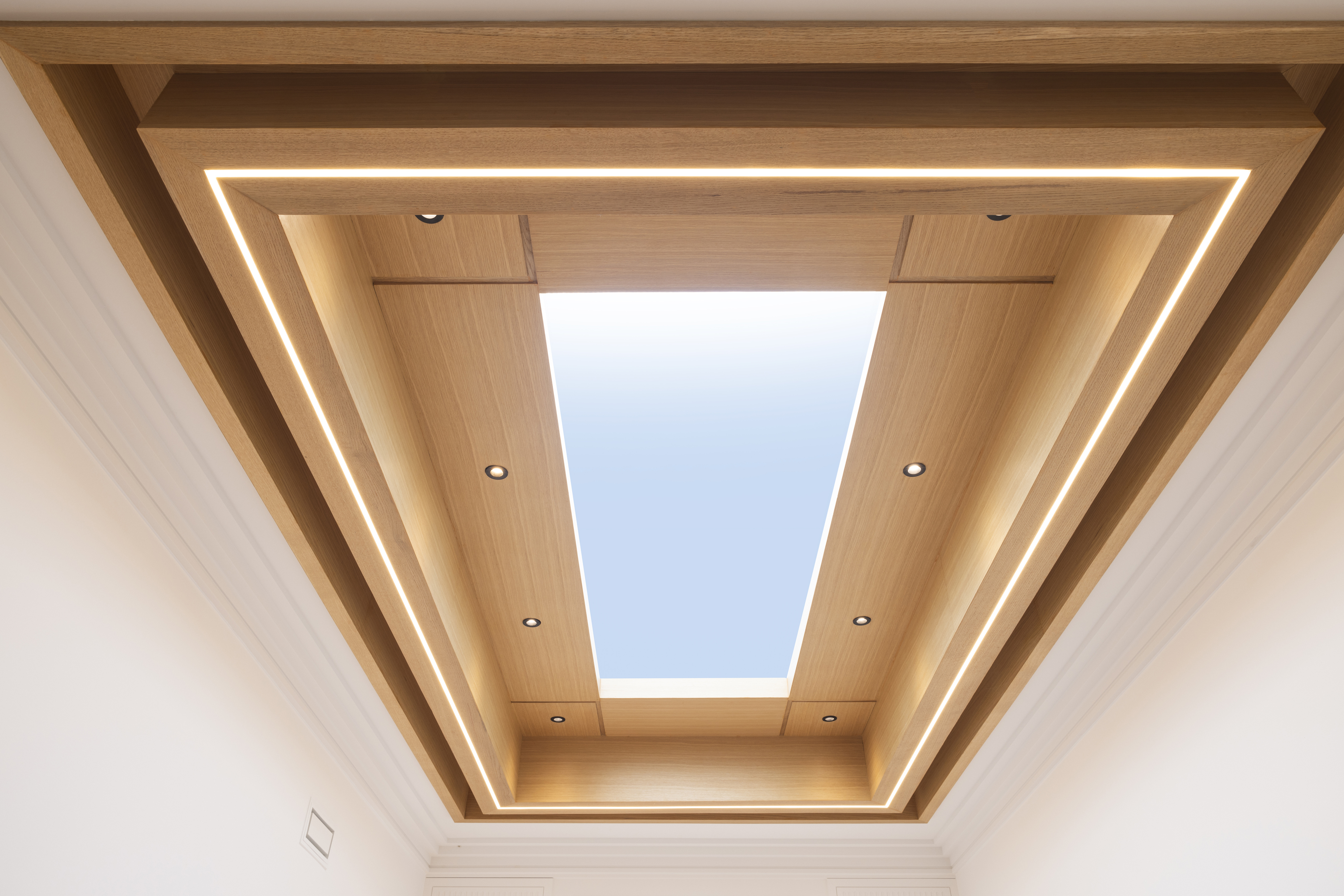 Recessed skylight framed by wood ceiling panels and integrated lighting