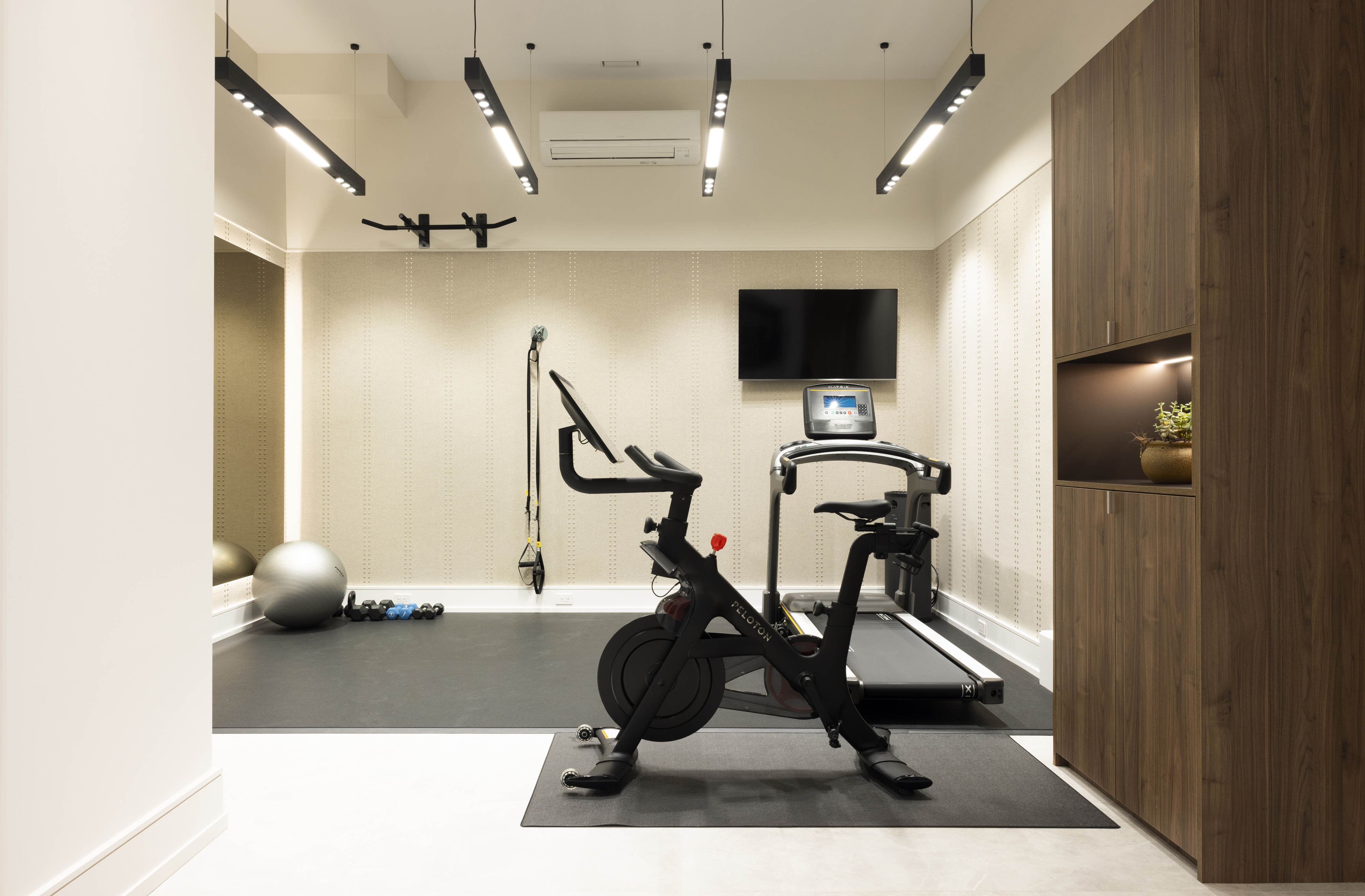 Home gym with exercise bike, treadmill, wall-mounted television, and mirrored walls