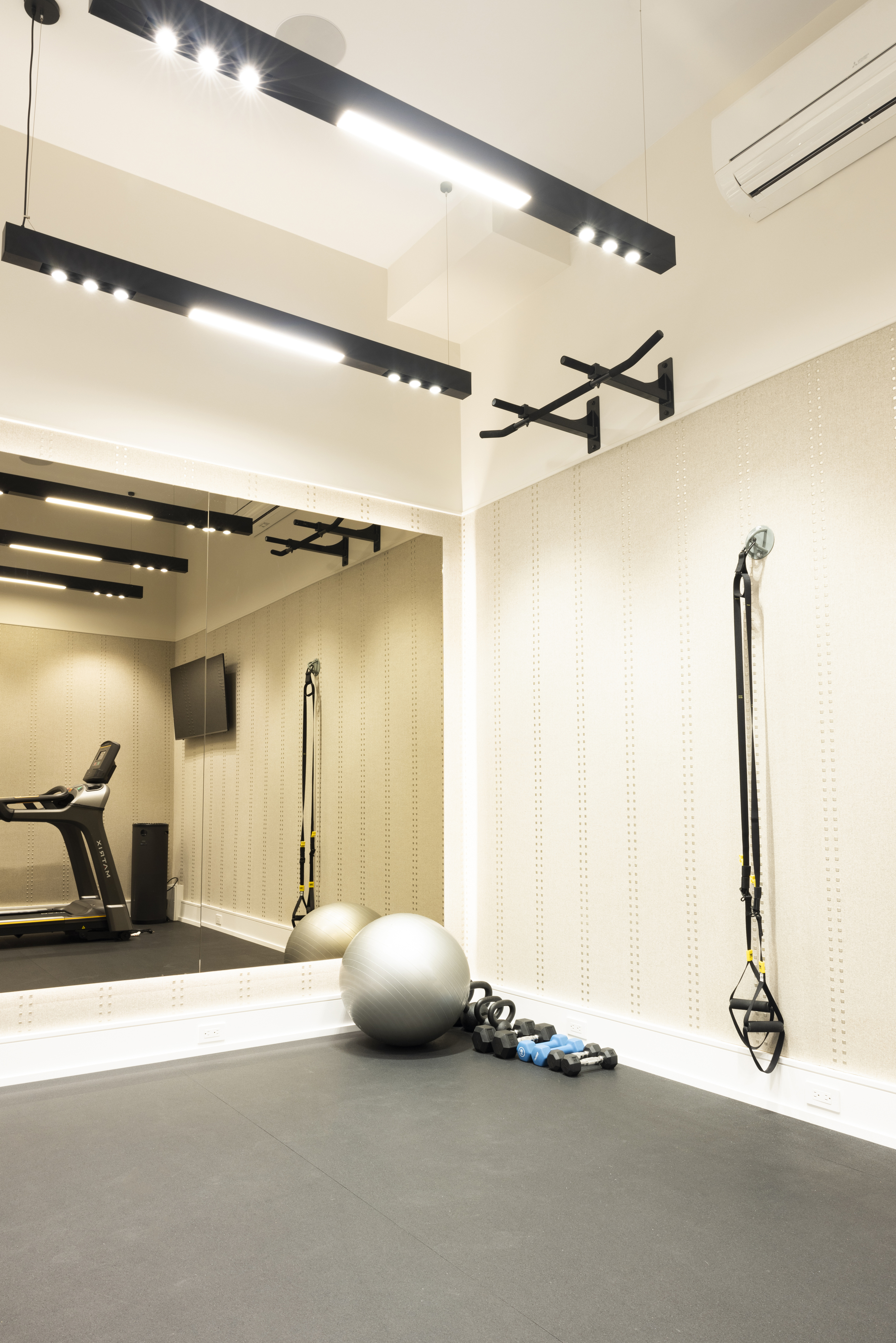 Home gym with exercise bike, treadmill, wall-mounted television, and mirrored walls