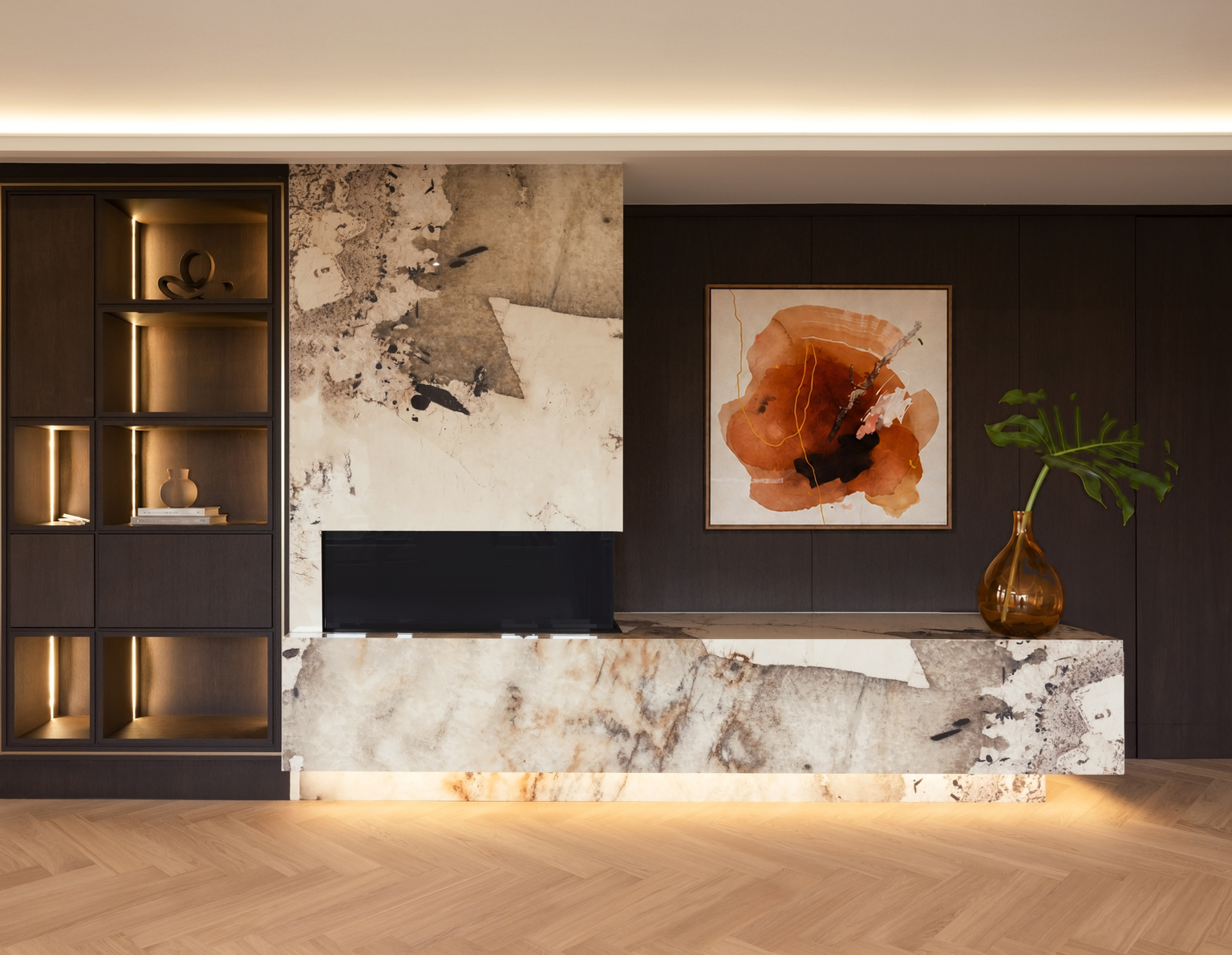 Dark feature wall with illuminated shelving, stone fireplace, artwork, and built-in cabinetry