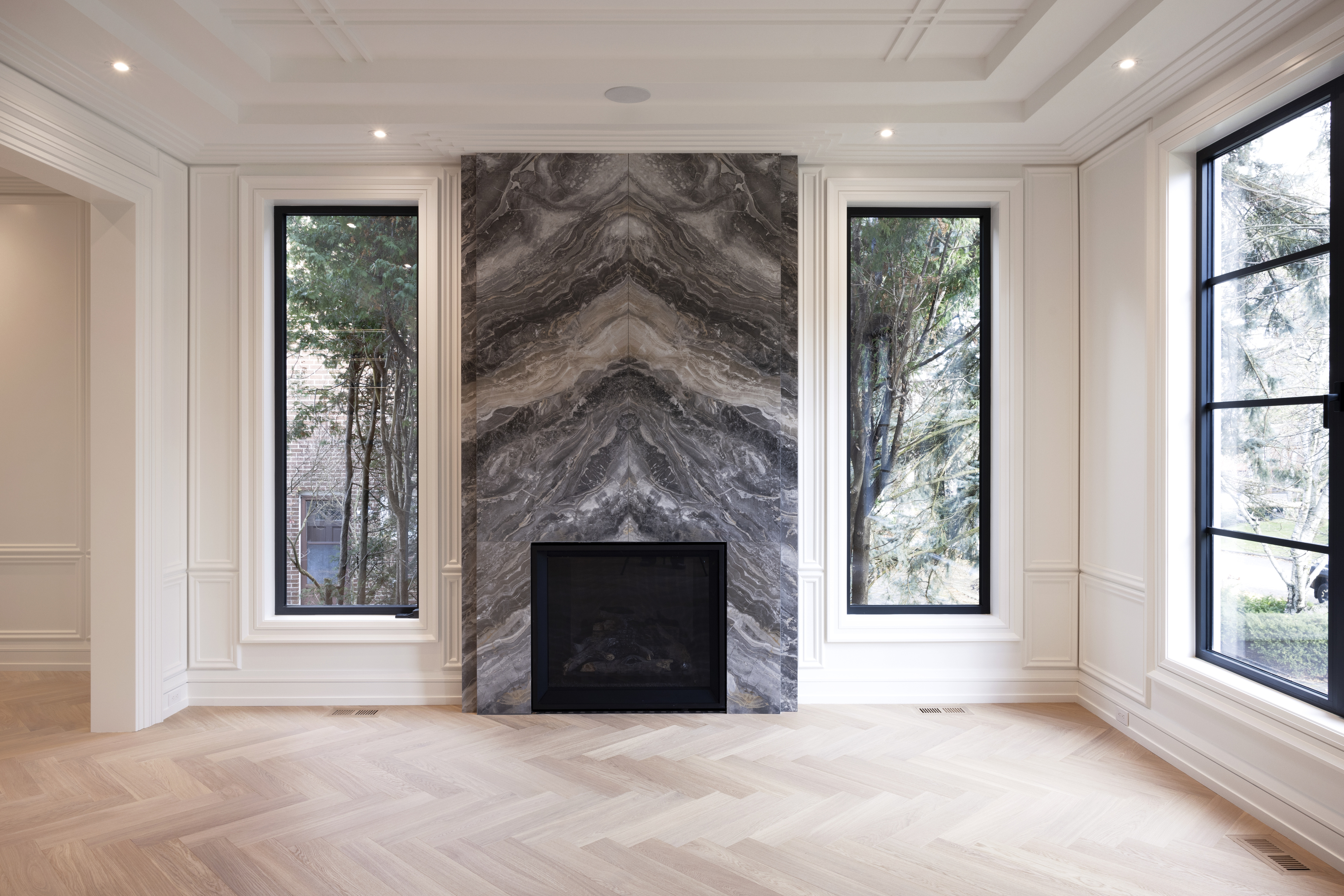 Stone fireplace centred between tall windows in a bright living room
