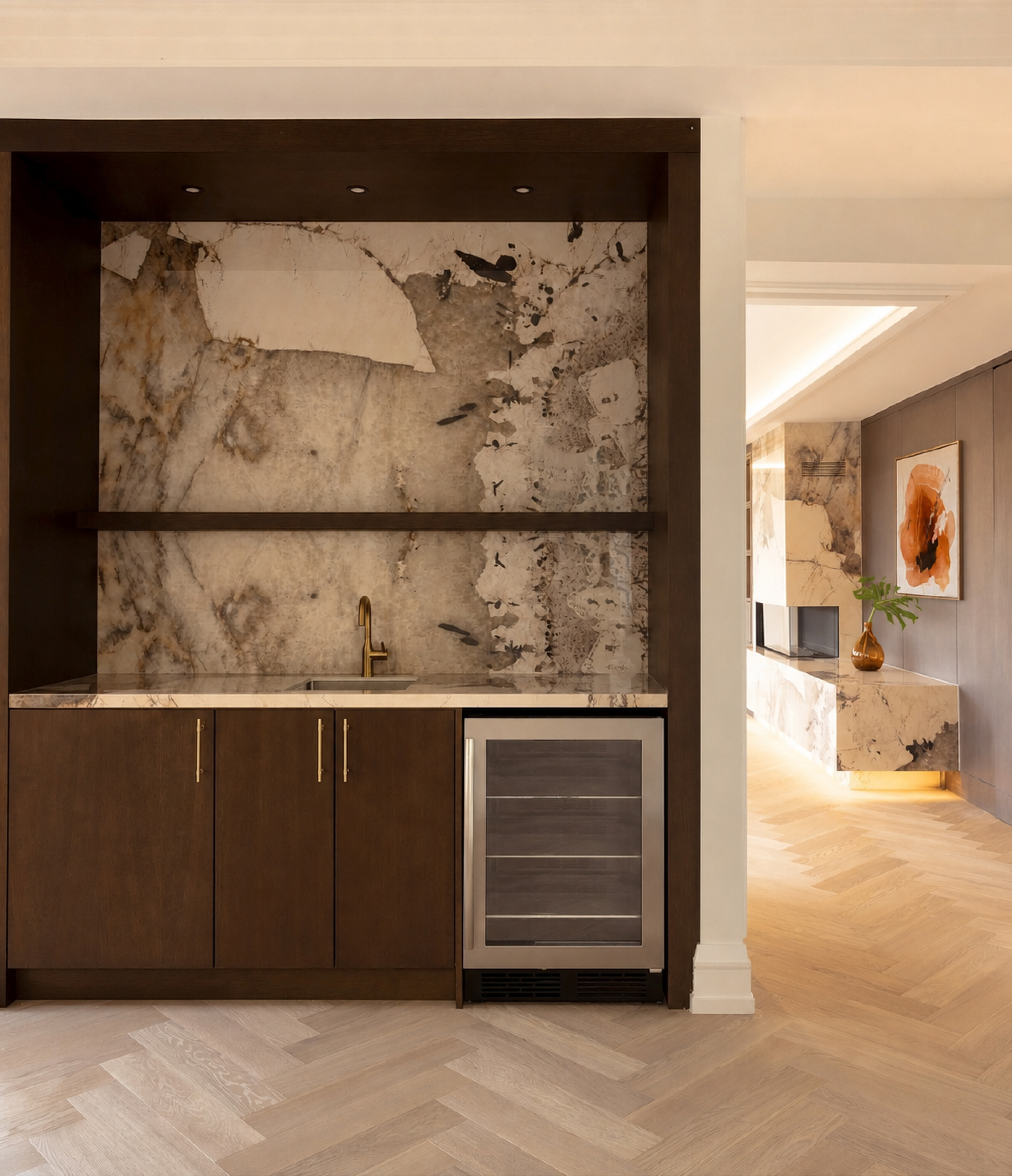 Dark wood home bar with stone backsplash, gold hardware, and beverage refrigerator
