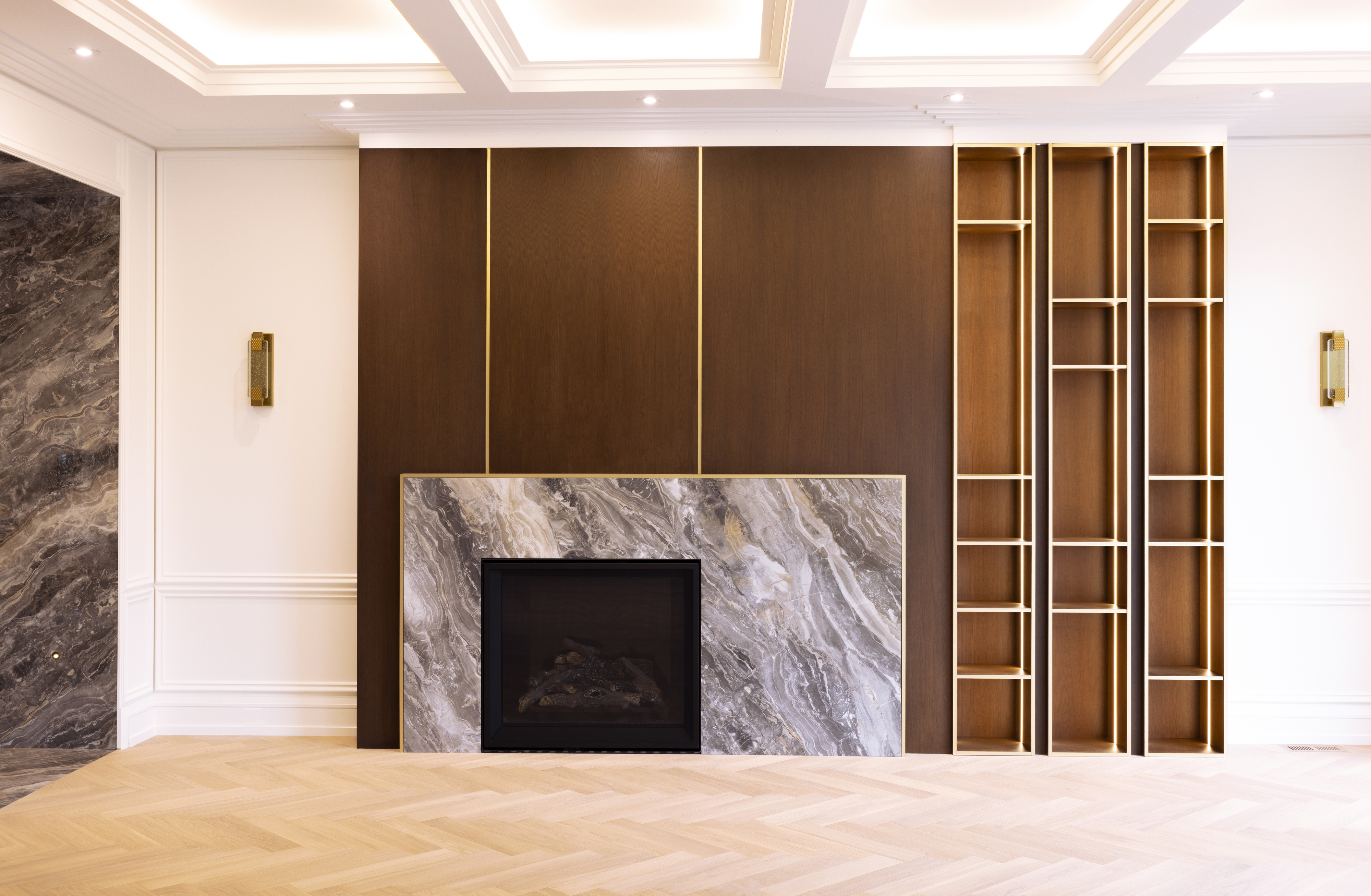 Modern fireplace with dramatic stone surround, dark wood shelving, and herringbone flooring