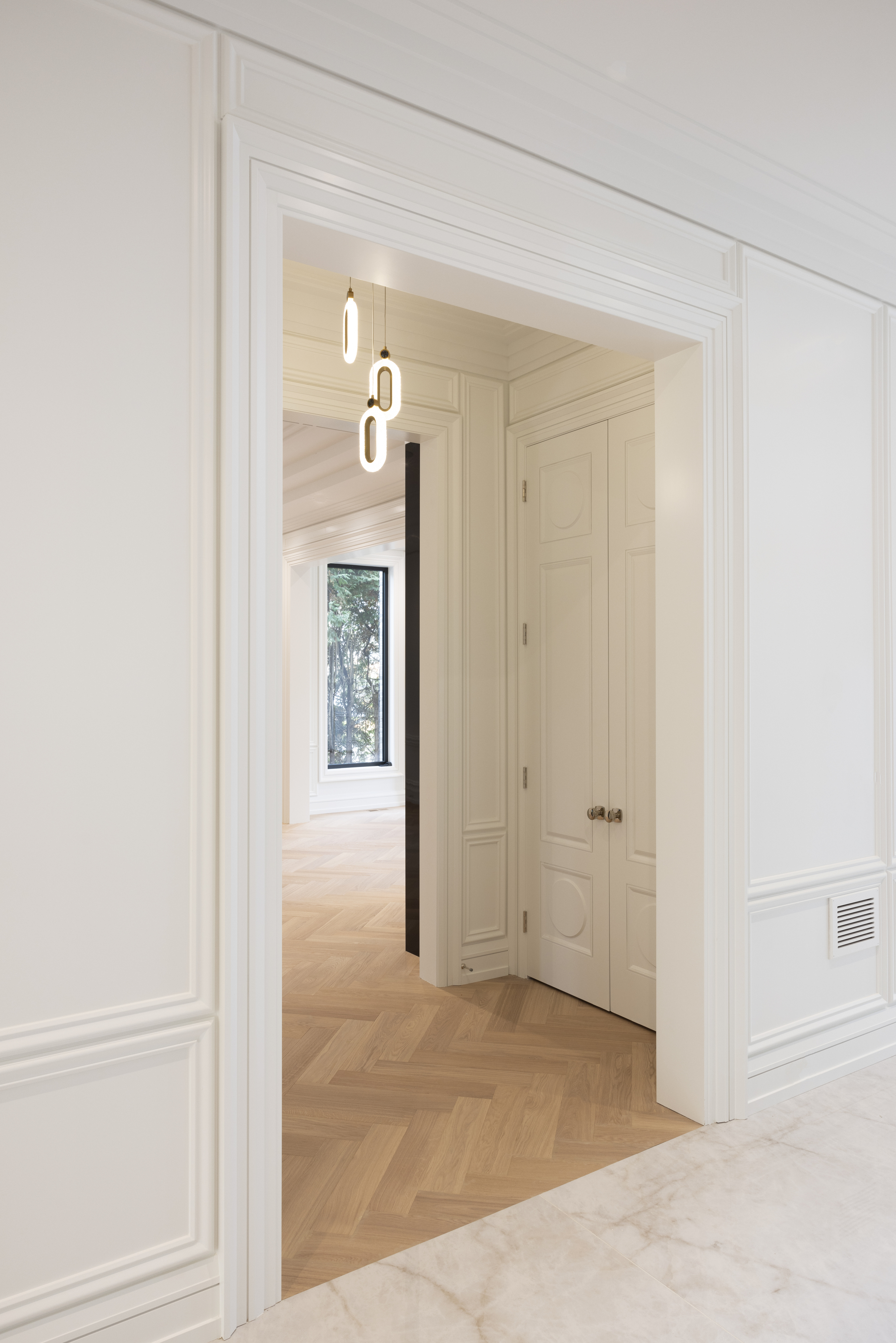 Bright interior hallway with detailed white wall panelling and wood flooring