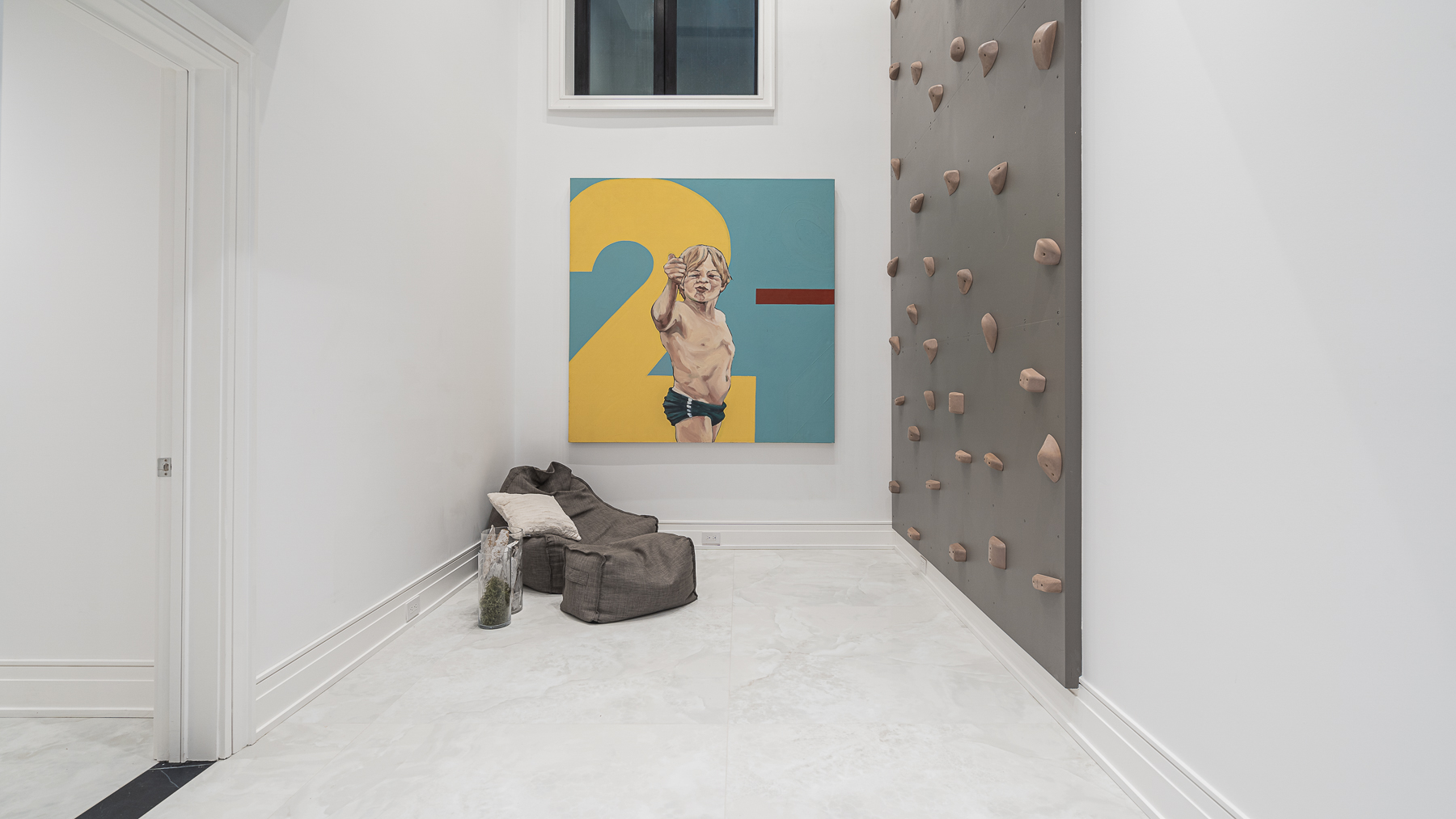 Indoor climbing room with rock-climbing wall, colourful artwork, and floor cushions