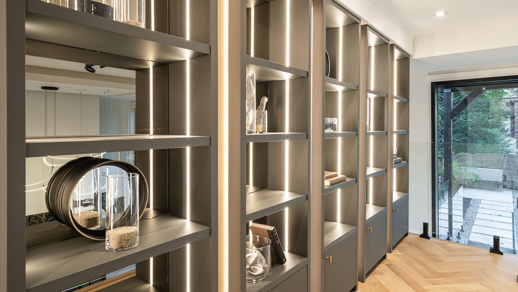 Custom grey display shelving with integrated vertical lighting and decorative objects