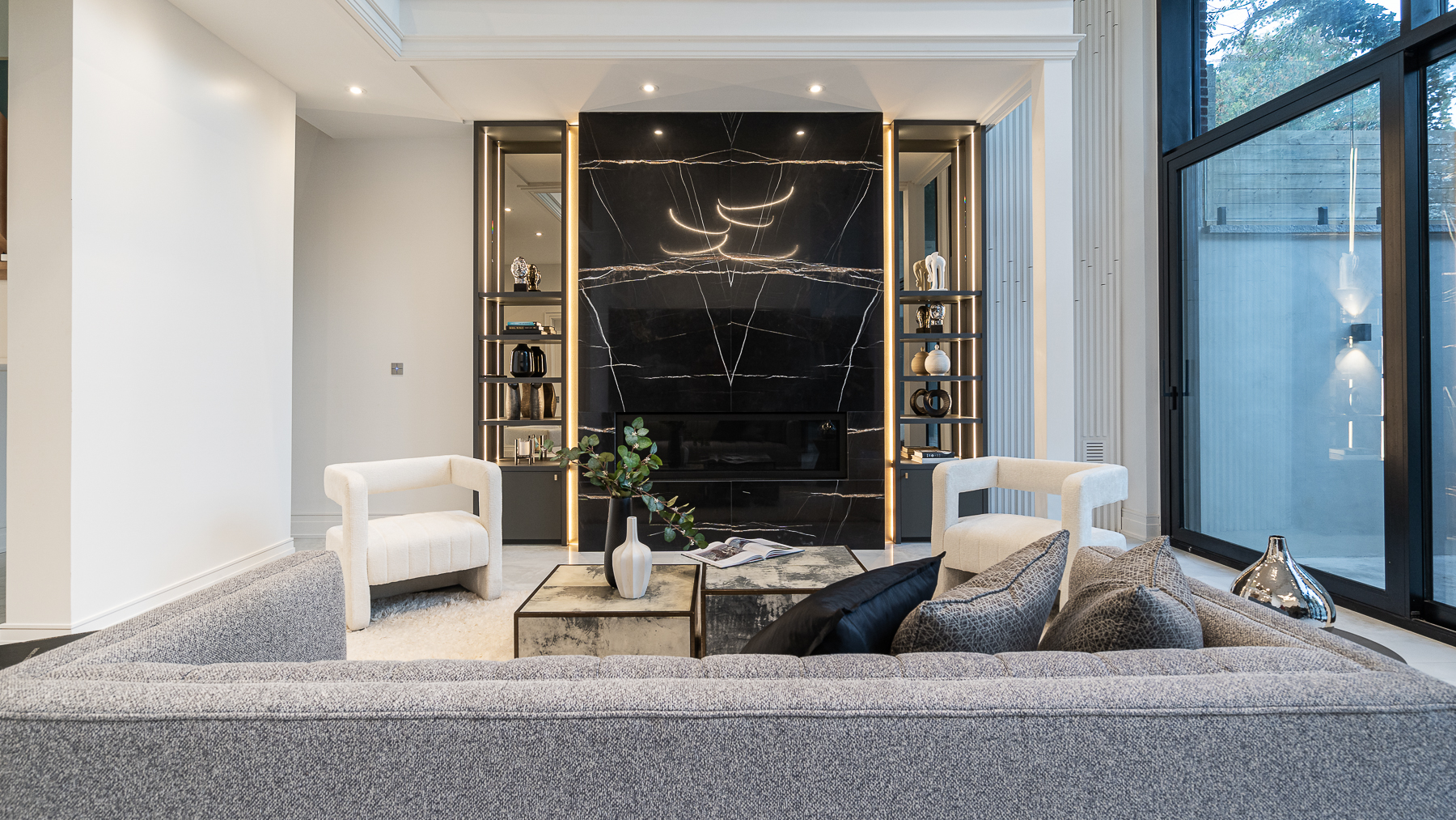Living room with dramatic black stone fireplace, built-in shelving, and neutral seating