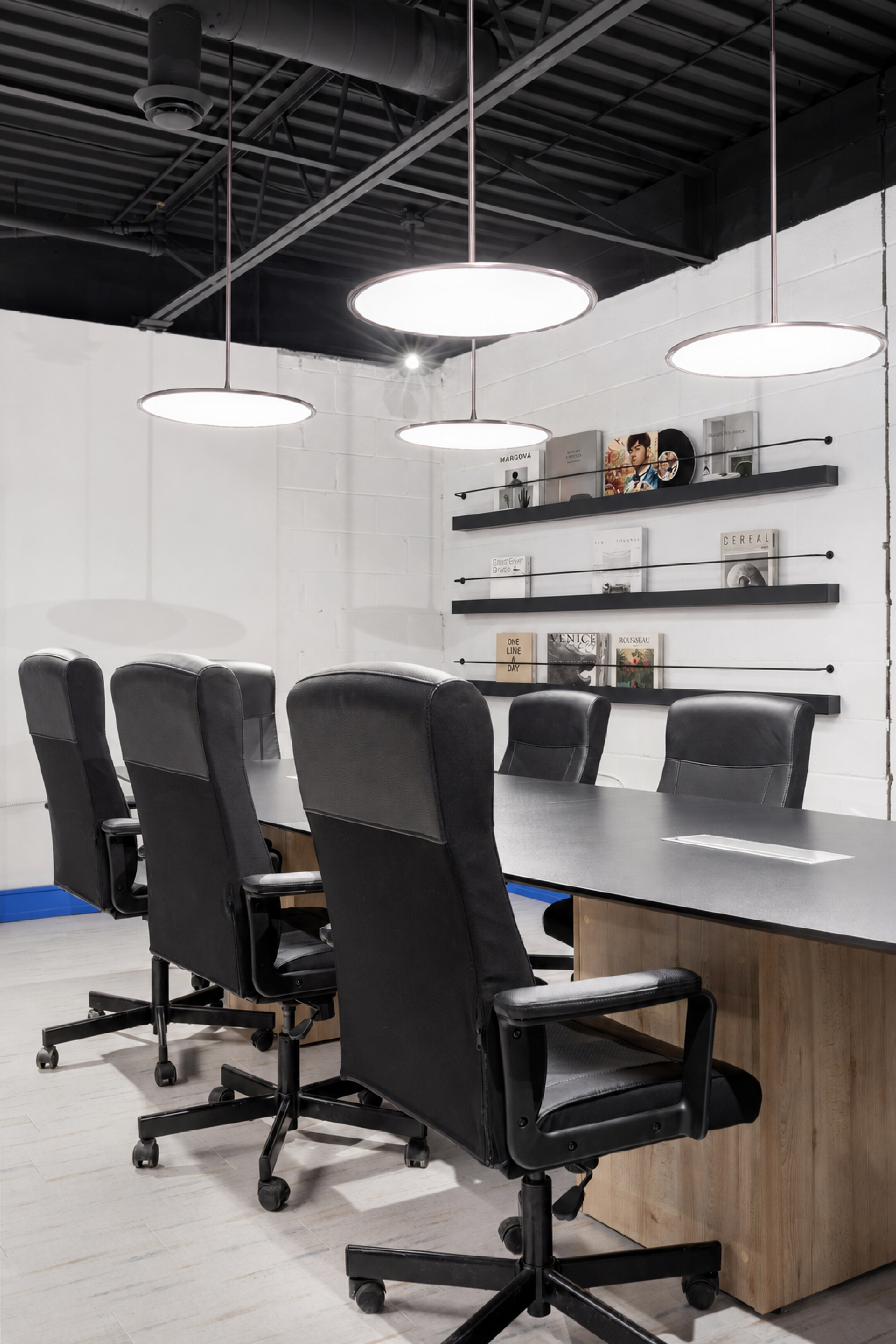 Conference room with black meeting table, leather chairs, pendant lights, and floating display shelves