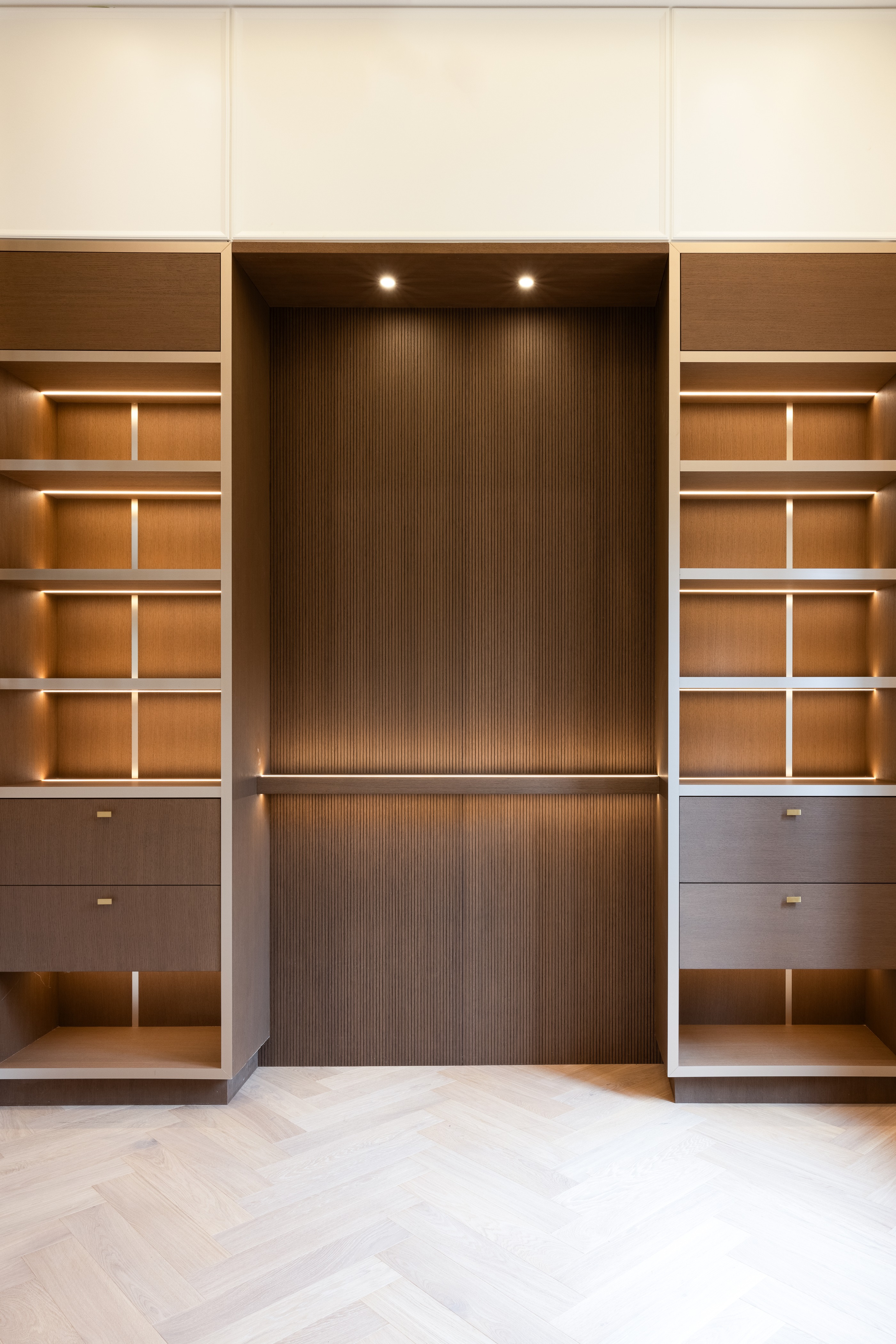 Close-up of dark wood shelving, fluted wall panels, and illuminated display niches