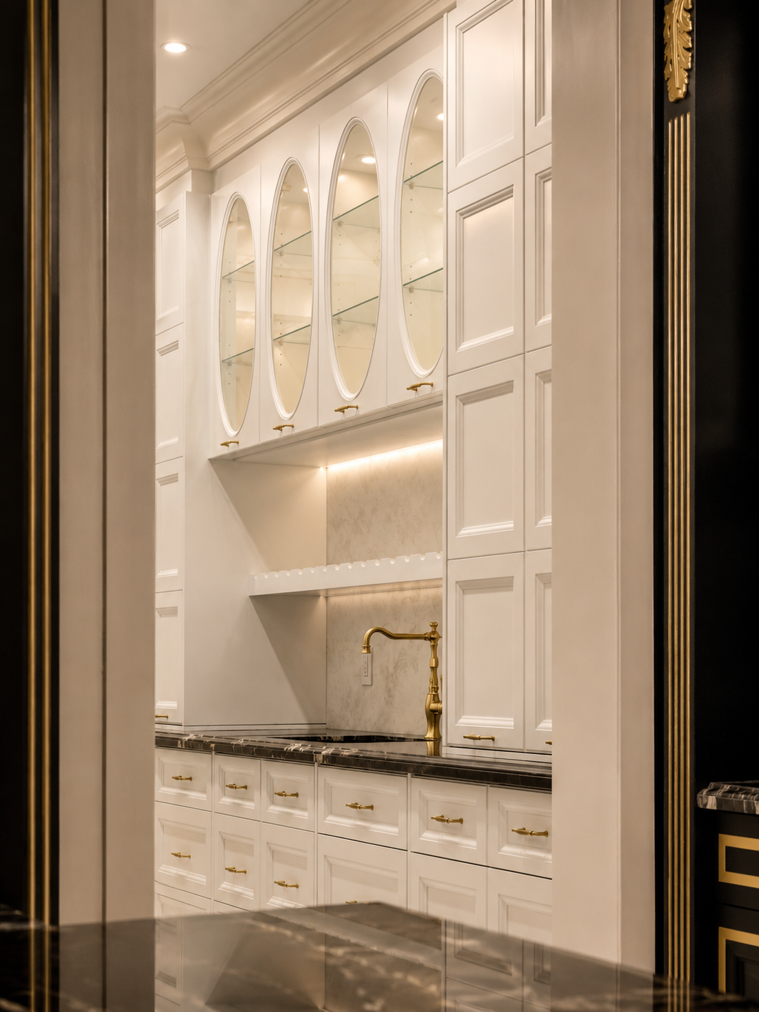 White built-in cabinetry with glass-front cupboards, marble countertop, and gold faucet