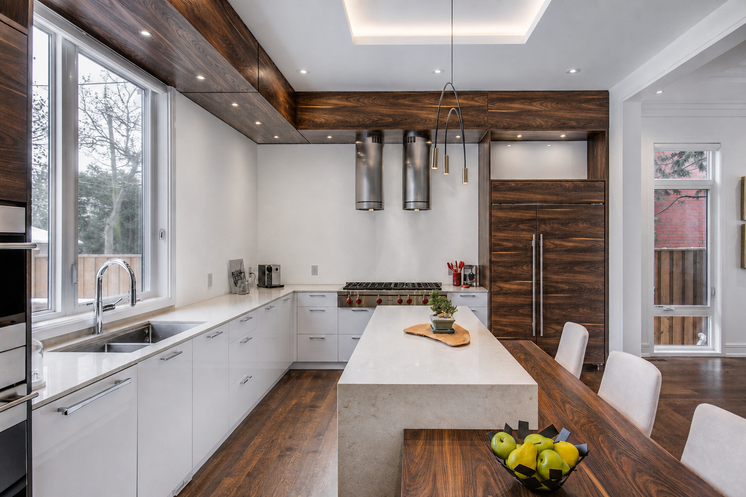Bright kitchen with white cabinetry, stone island, dark wood accents, and pendant lighting