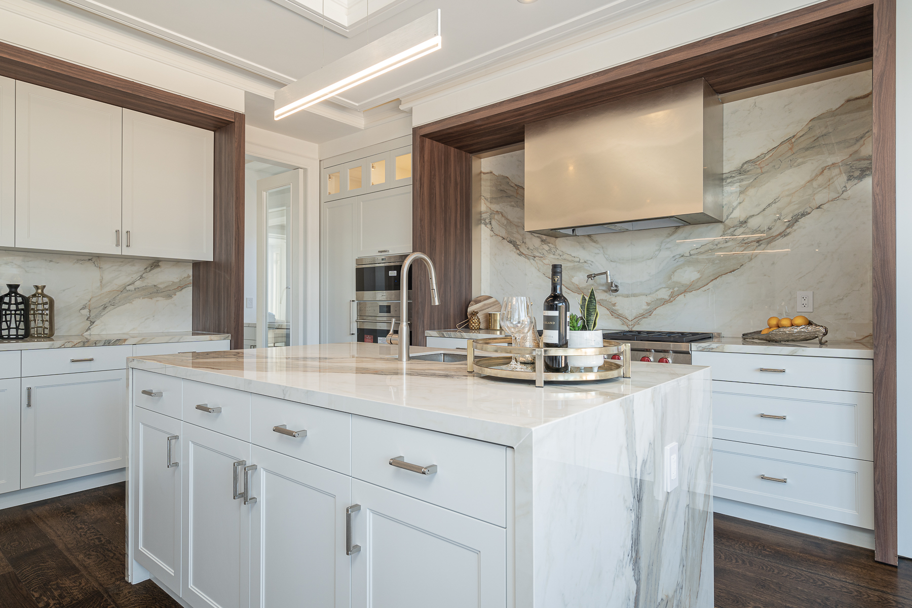 Bright kitchen with white cabinetry, marble island, and marble backsplash