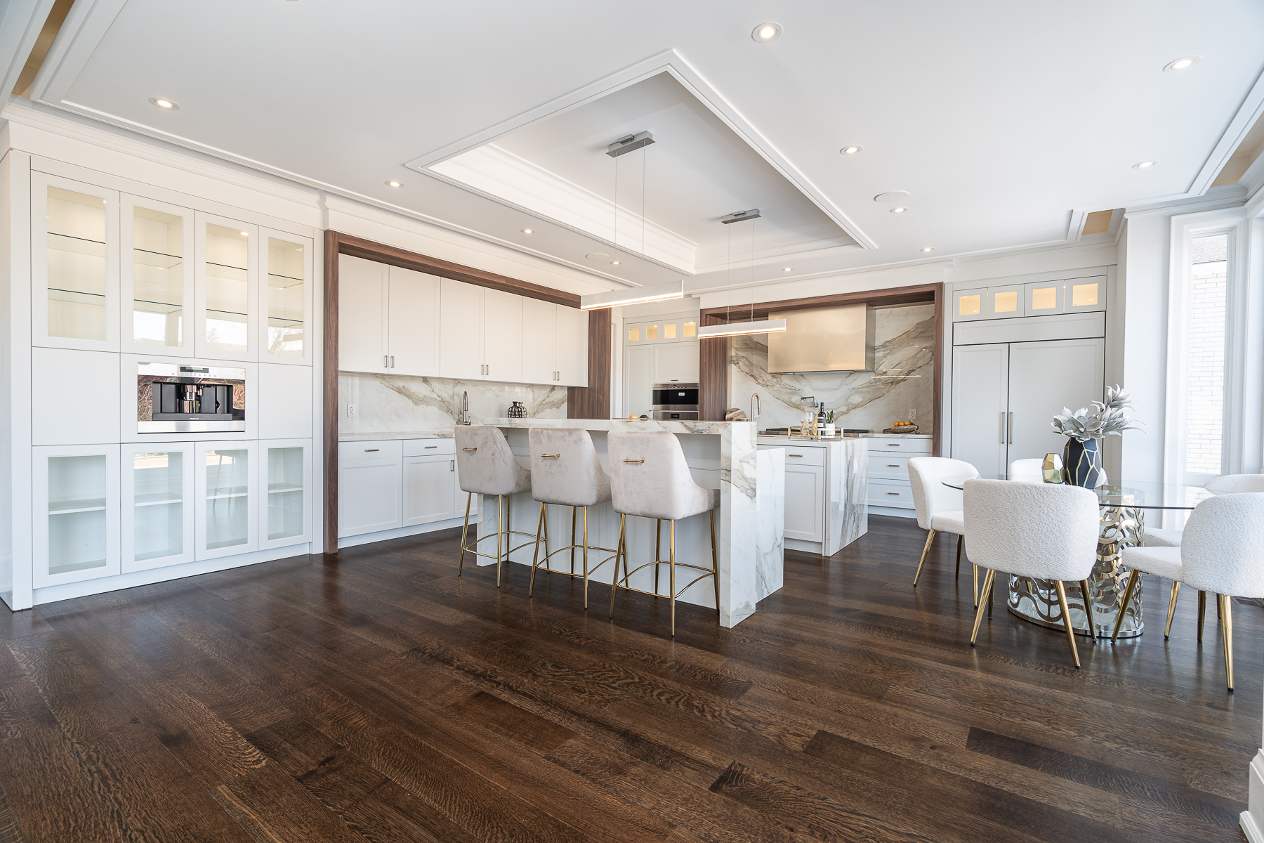 Open kitchen and dining area with white cabinetry, marble island, and dark wood flooring