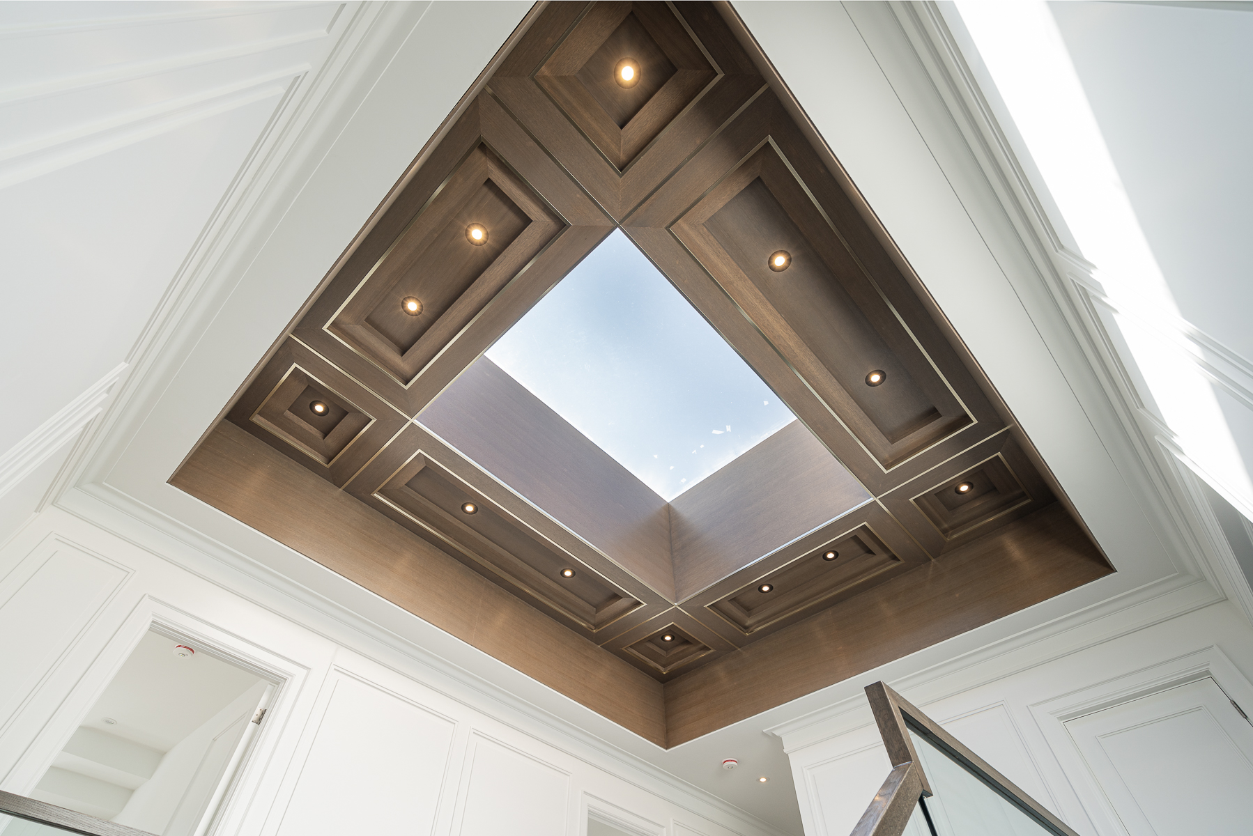 Large skylight framed by dark wood ceiling panels and recessed lighting