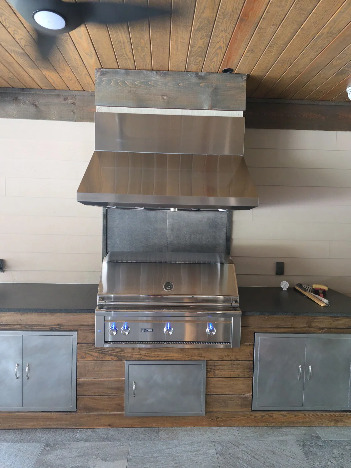 Lynx built-in grill and stainless vent hood in an outdoor kitchen
