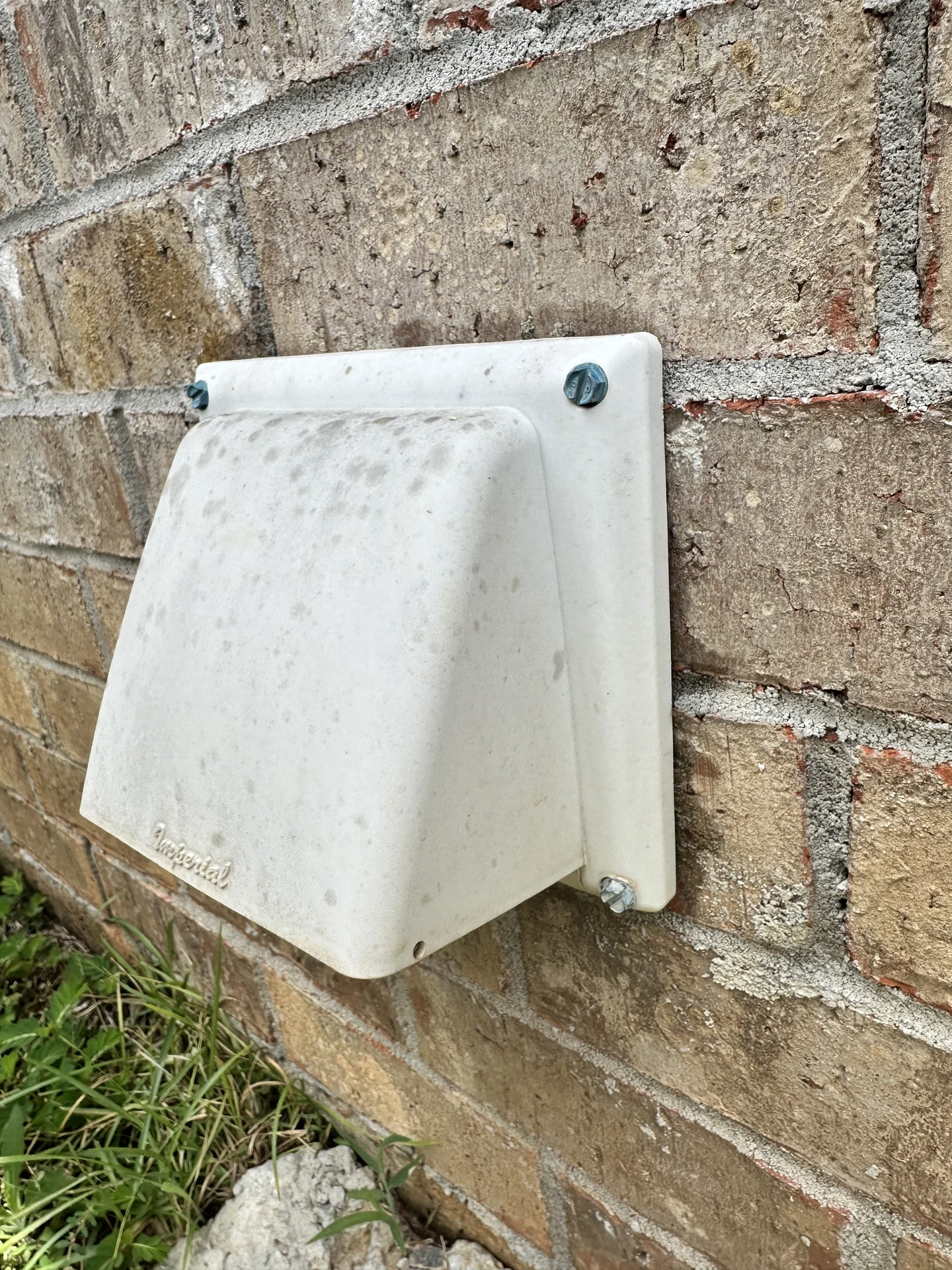 Side view of an exterior dryer vent termination on a brick home