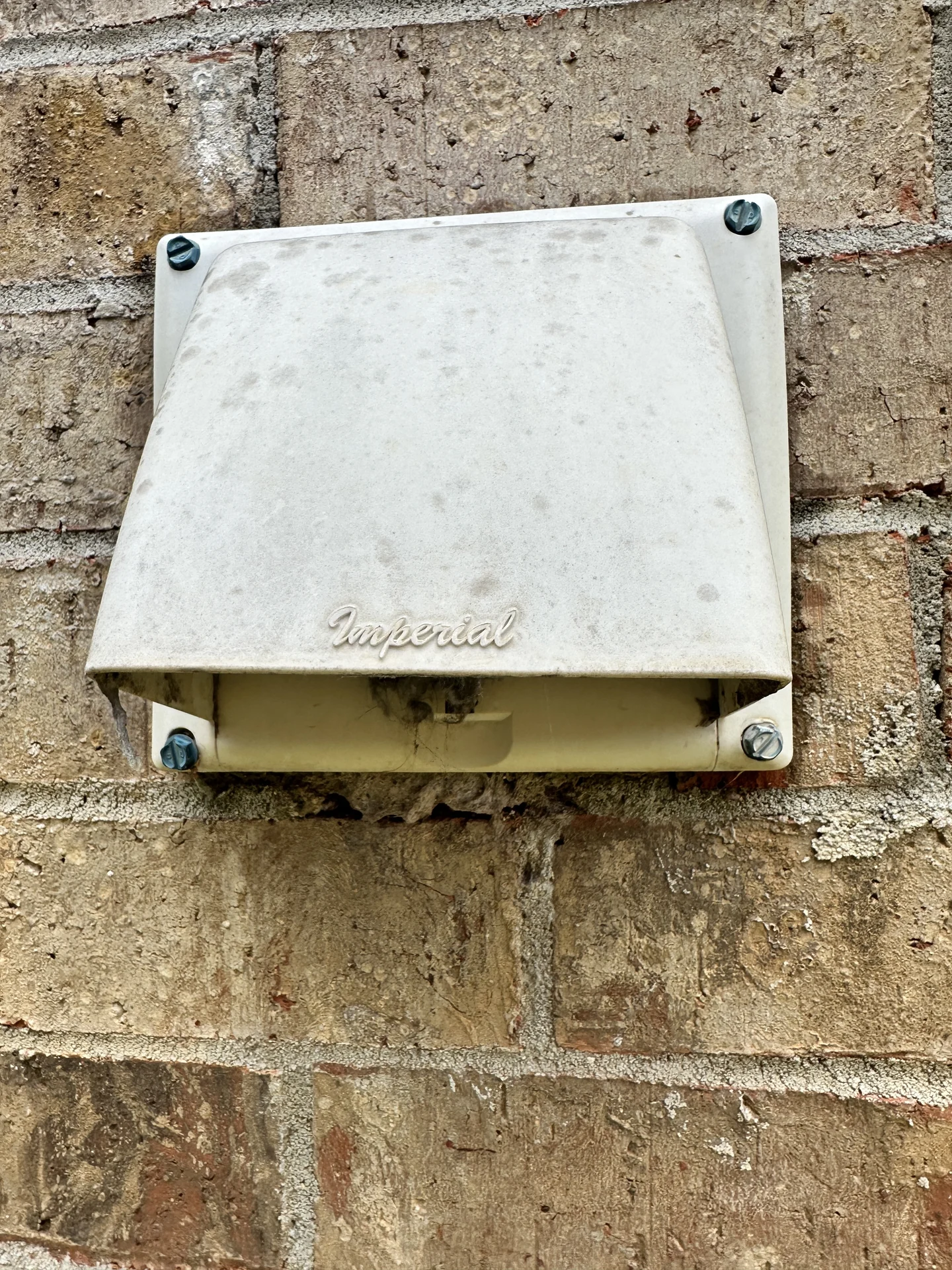 Open exterior dryer vent termination on a brick home
