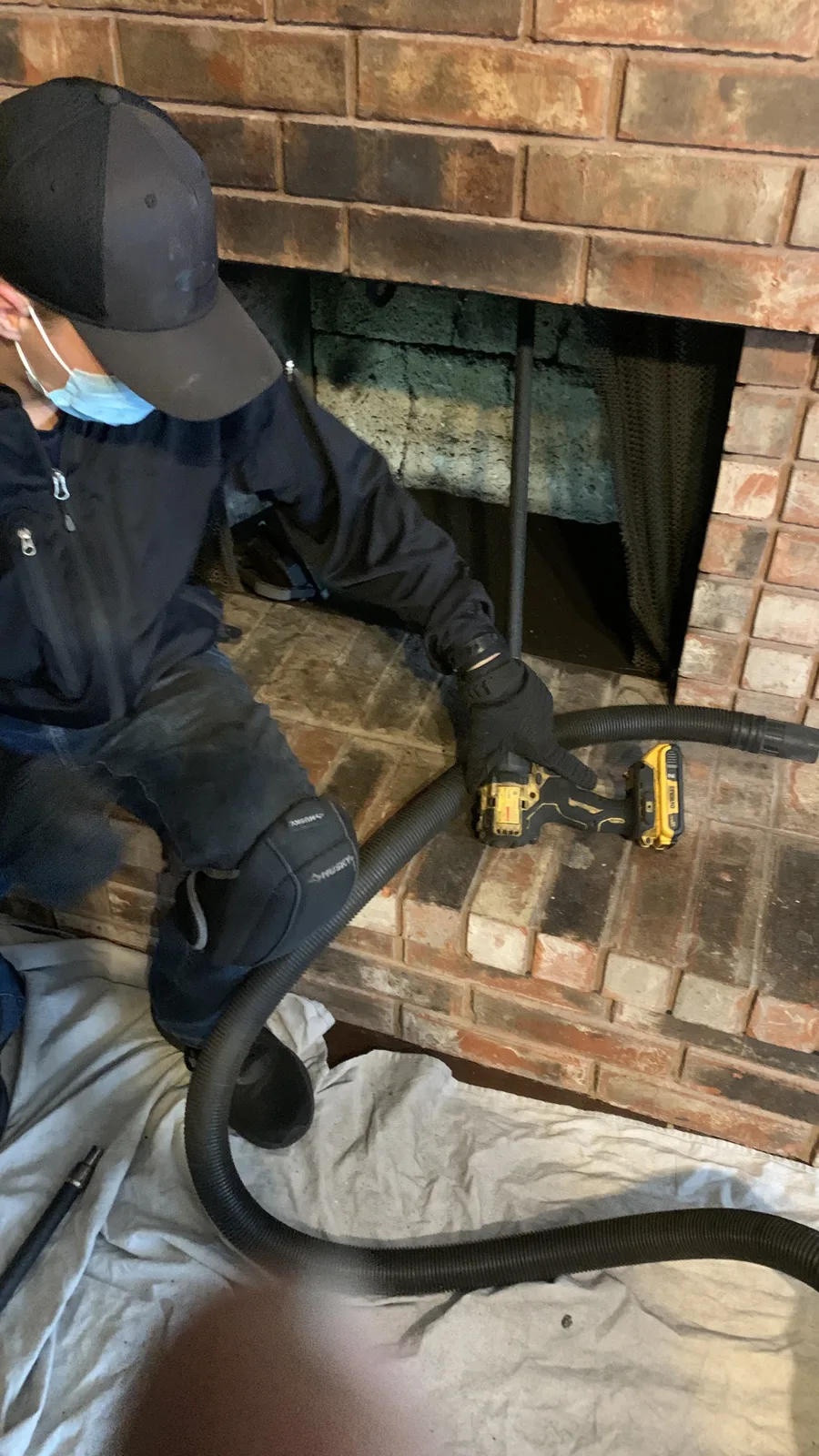 Chimney sweep with HEPA vacuum and drop cloths protecting the hearth