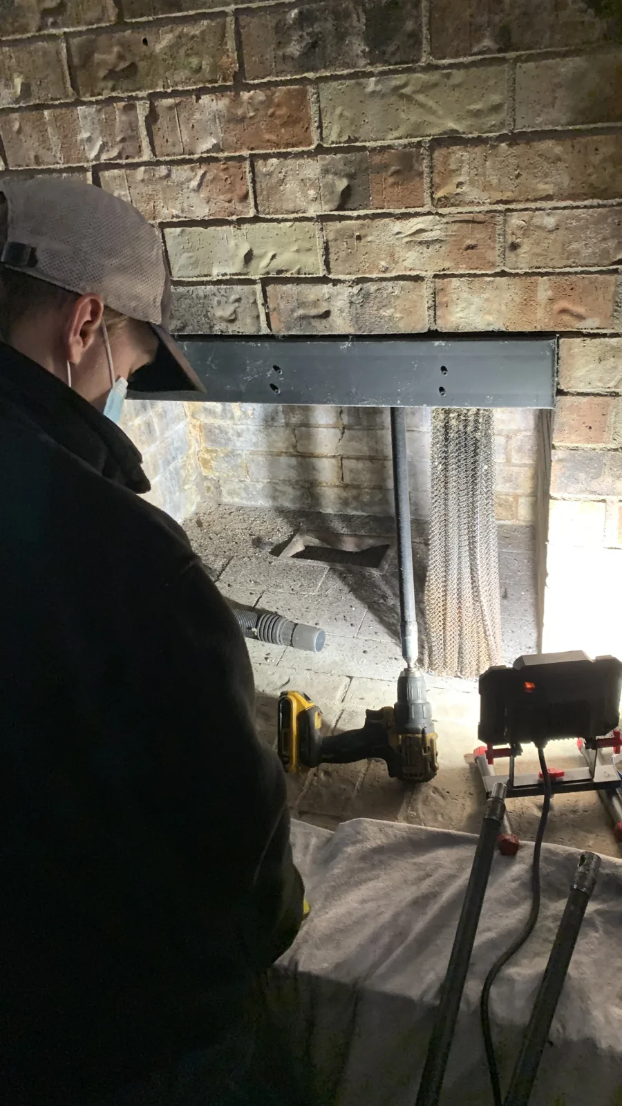 1st Choice Residential technician sweeping a brick fireplace chimney