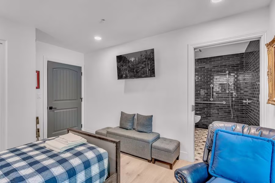 Suite with a bed, sitting area, recliner, and open door to the private bathroom