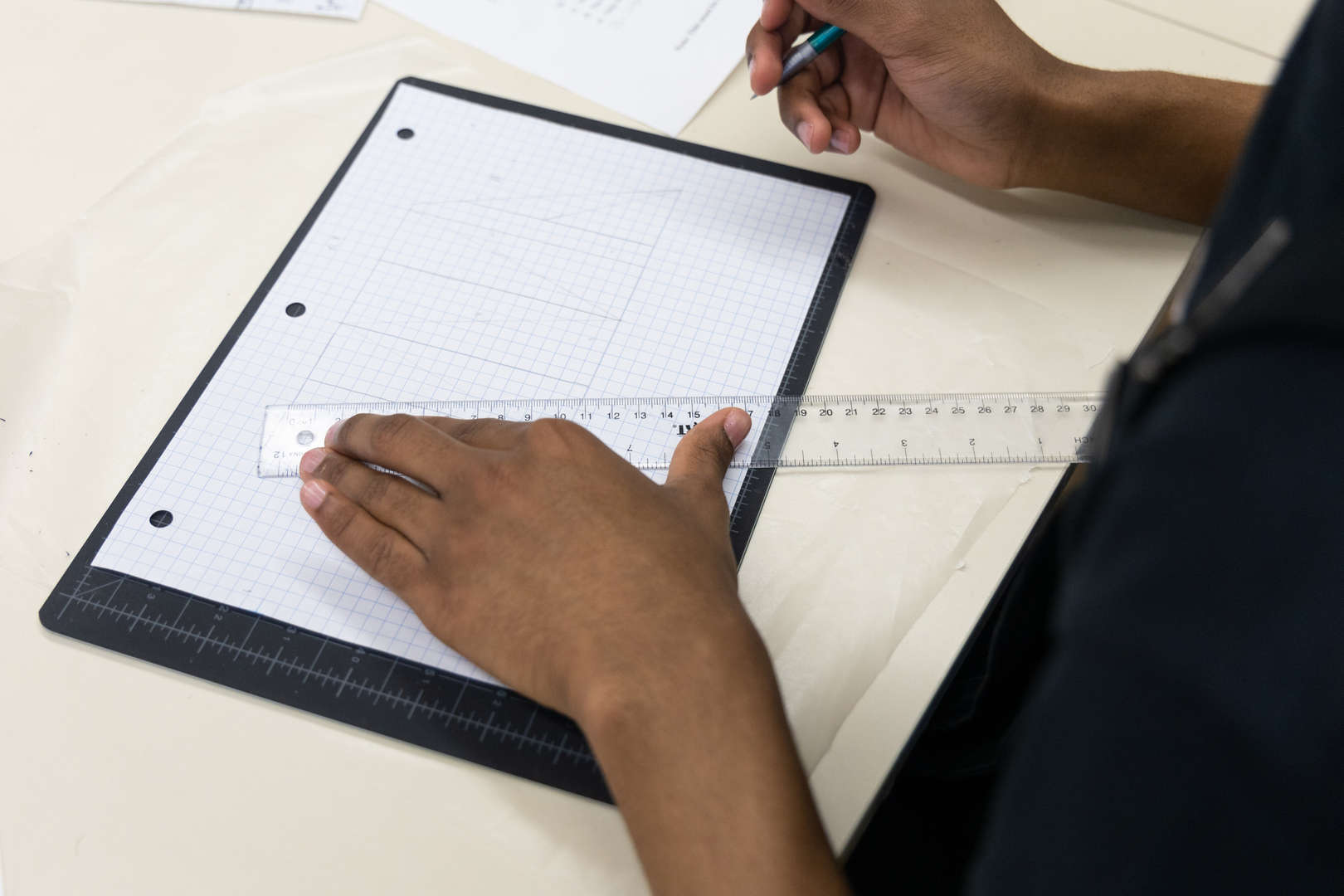 Student drawing precise lines on graph paper using a ruler