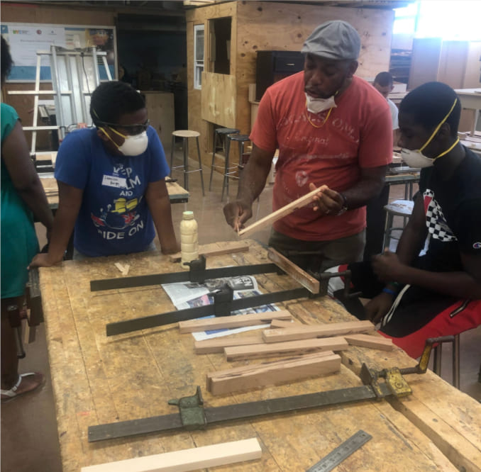Instructor teaching students woodworking skills in a workshop classroom